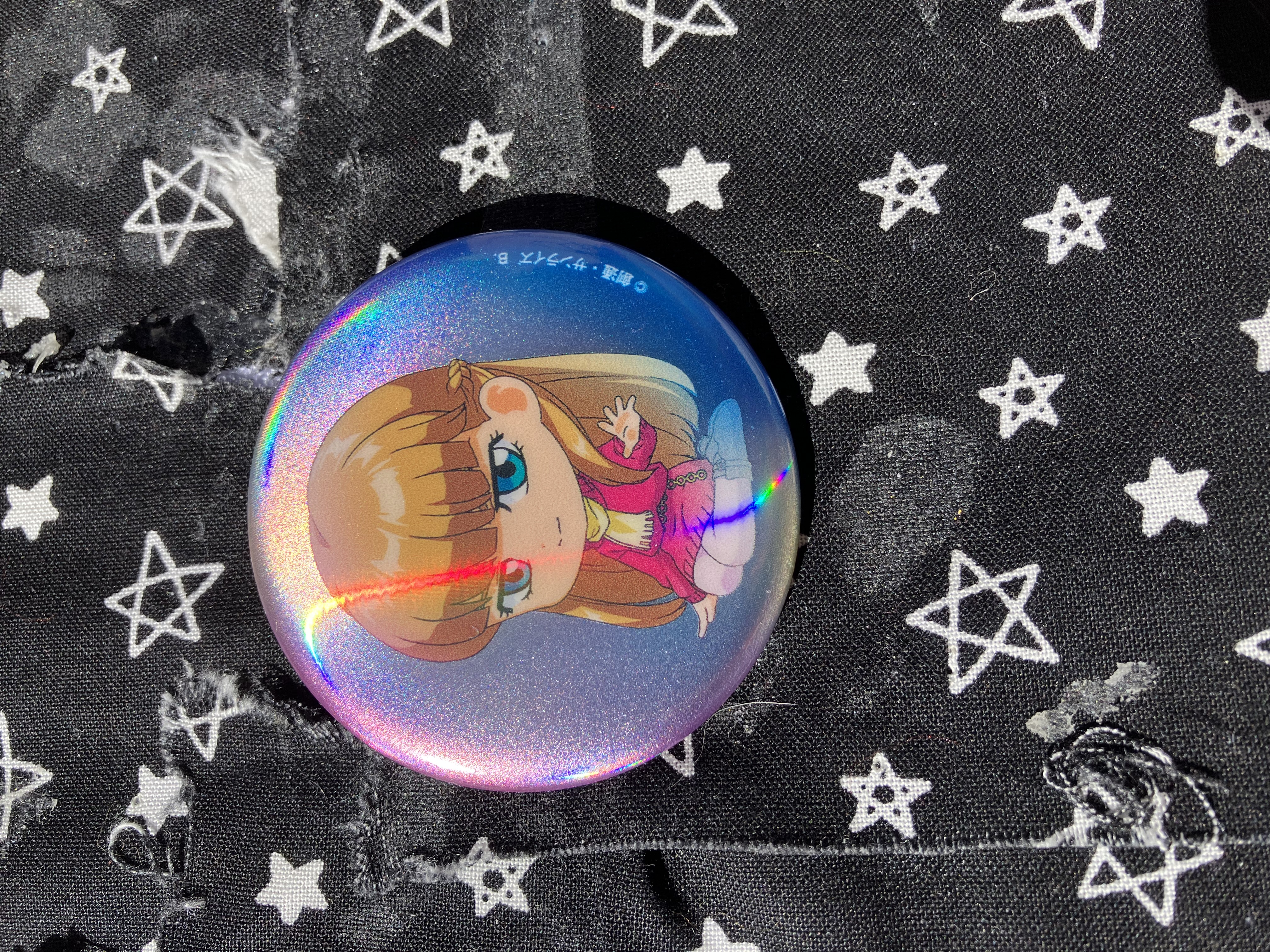 Holographic button that has chibi Gundam wing Relena in her pink sweater dress and yellow scarf.