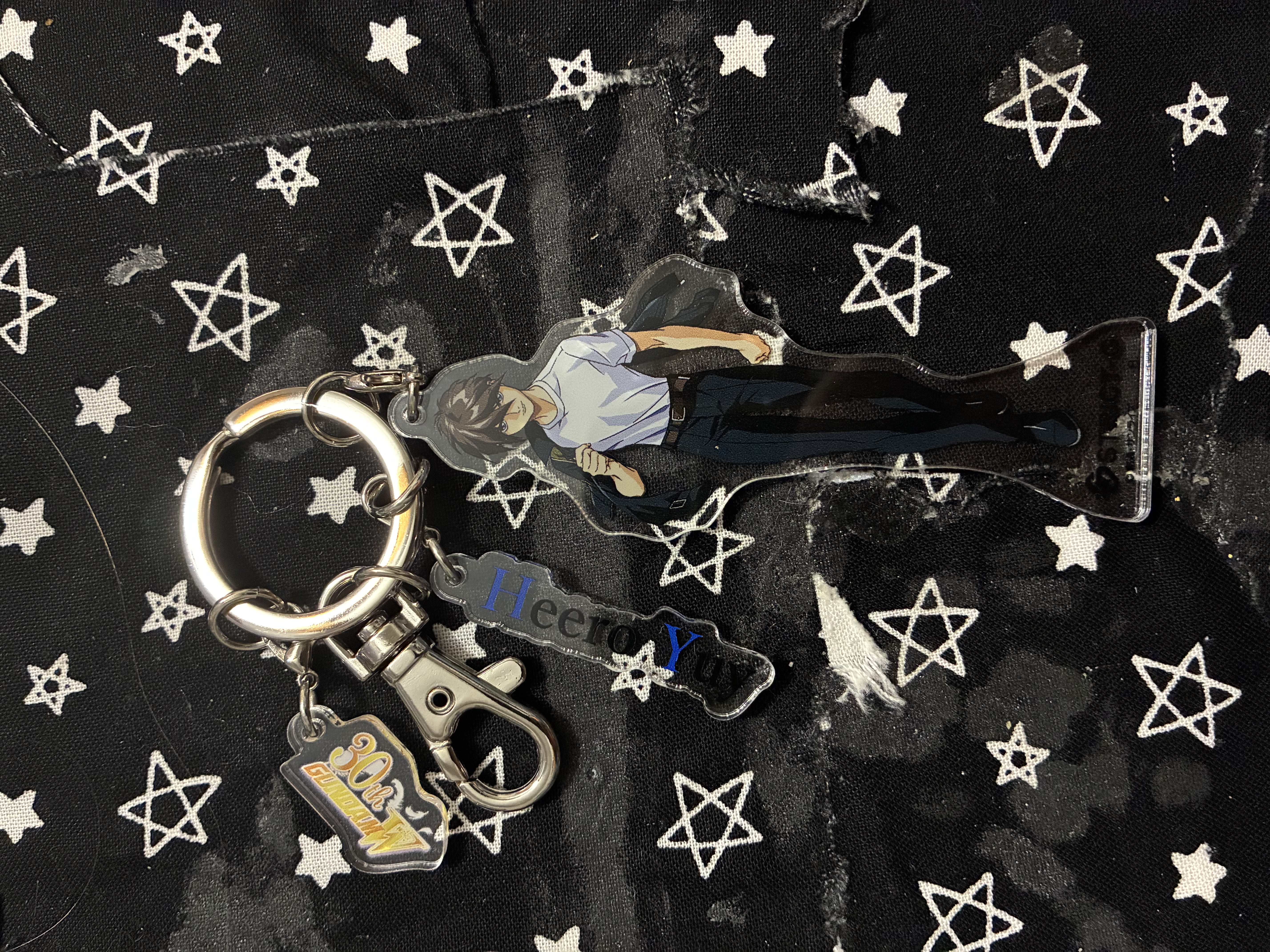 Acrylic keychain of Heero in his preventers uniform with his jacket held over his shoulder and
                his name plate plus gundam wing logo.
