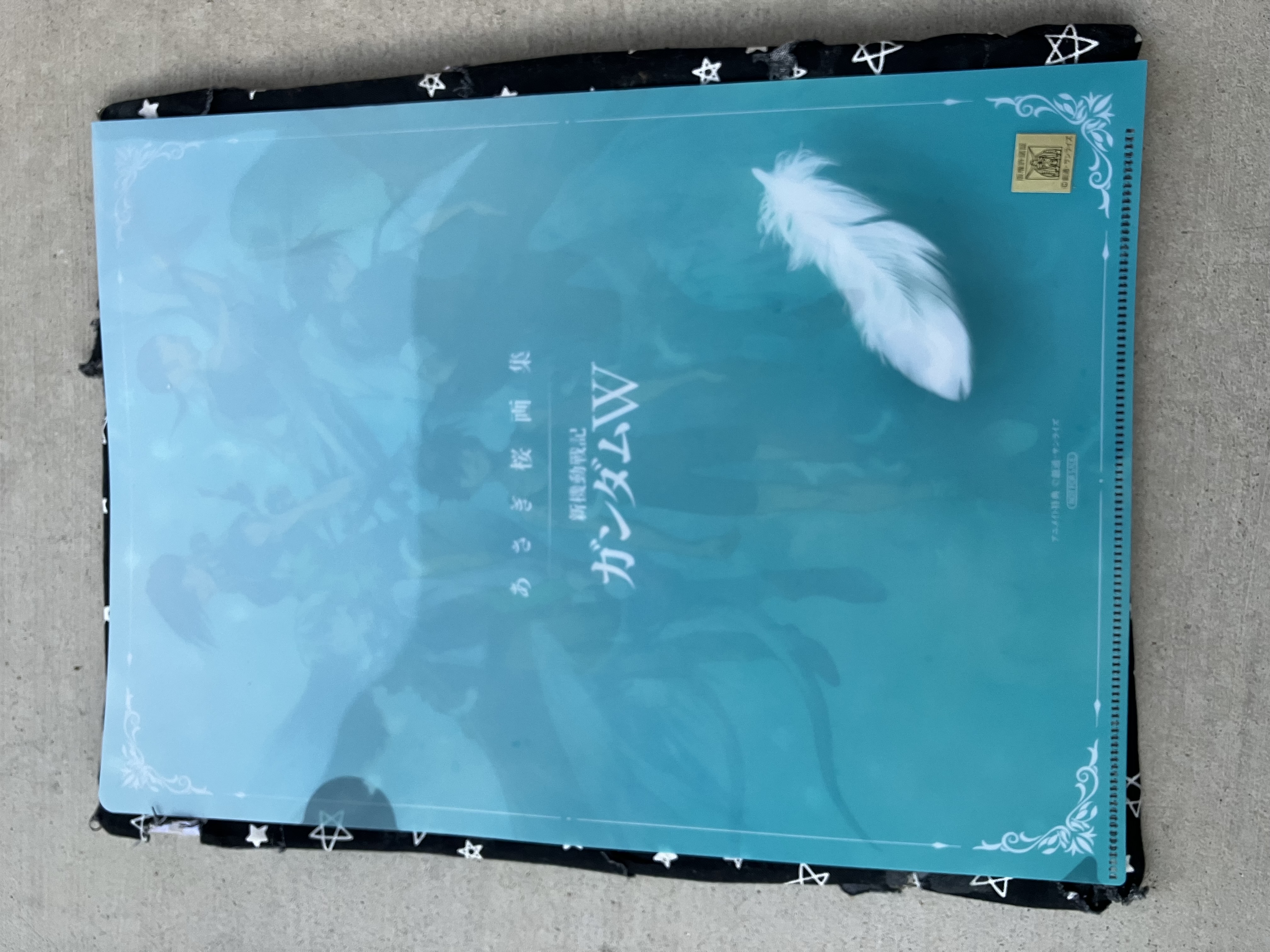 Back of clear file with the Gundam wing logo and a angel feather.