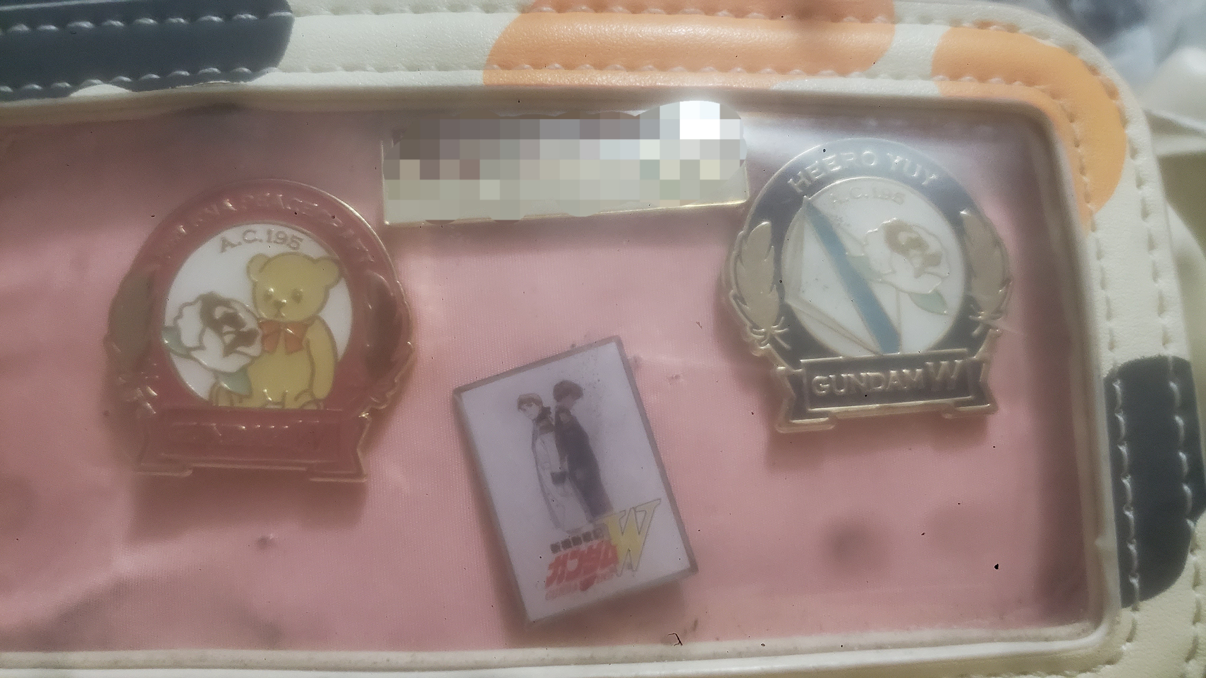 Gundam wing and food bank enamel pins in a fanny pack.