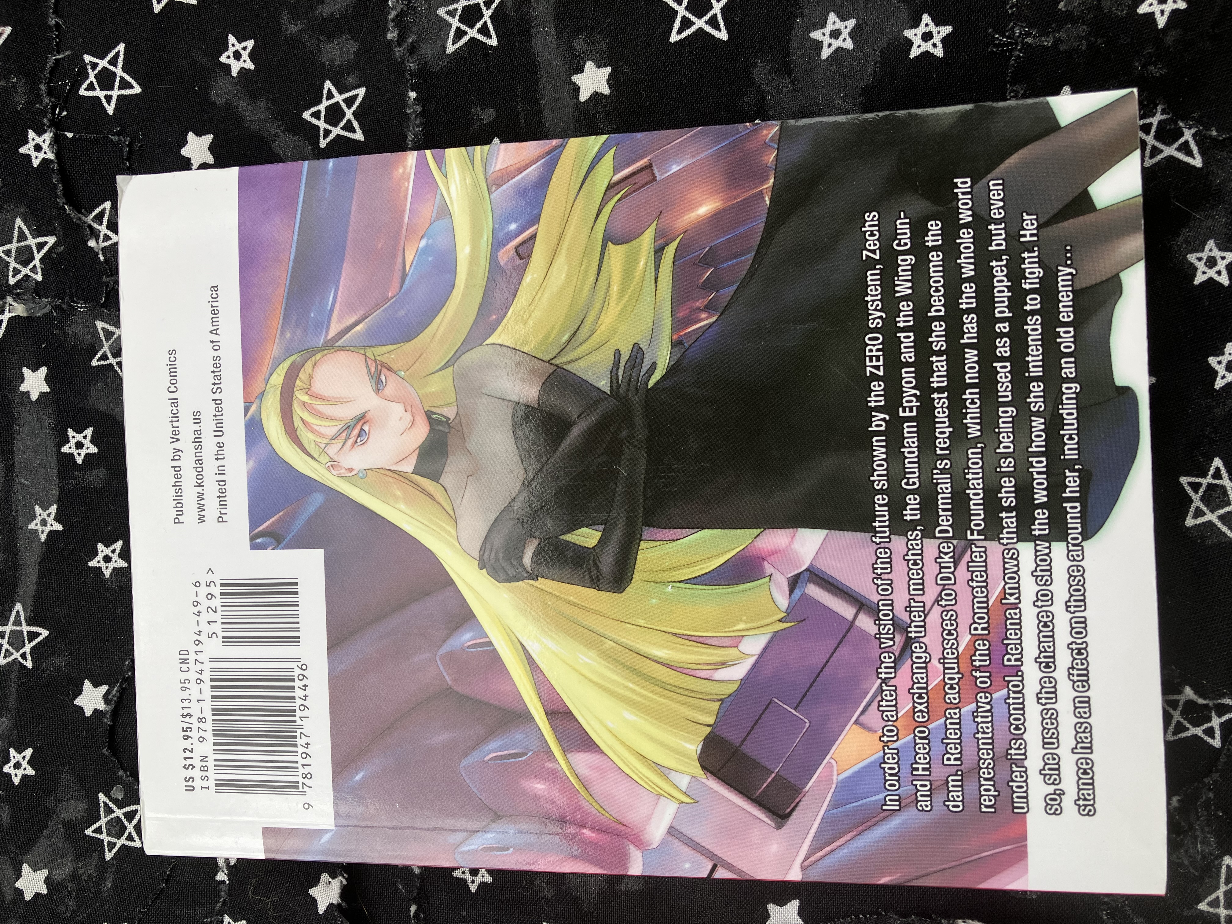 Back of volume 11 of the manga Mobile Suit Gundam Wing: Endless Waltz: Glory of the Losers with Dorothy in a black dress with wing zero's wing and gun behind her.