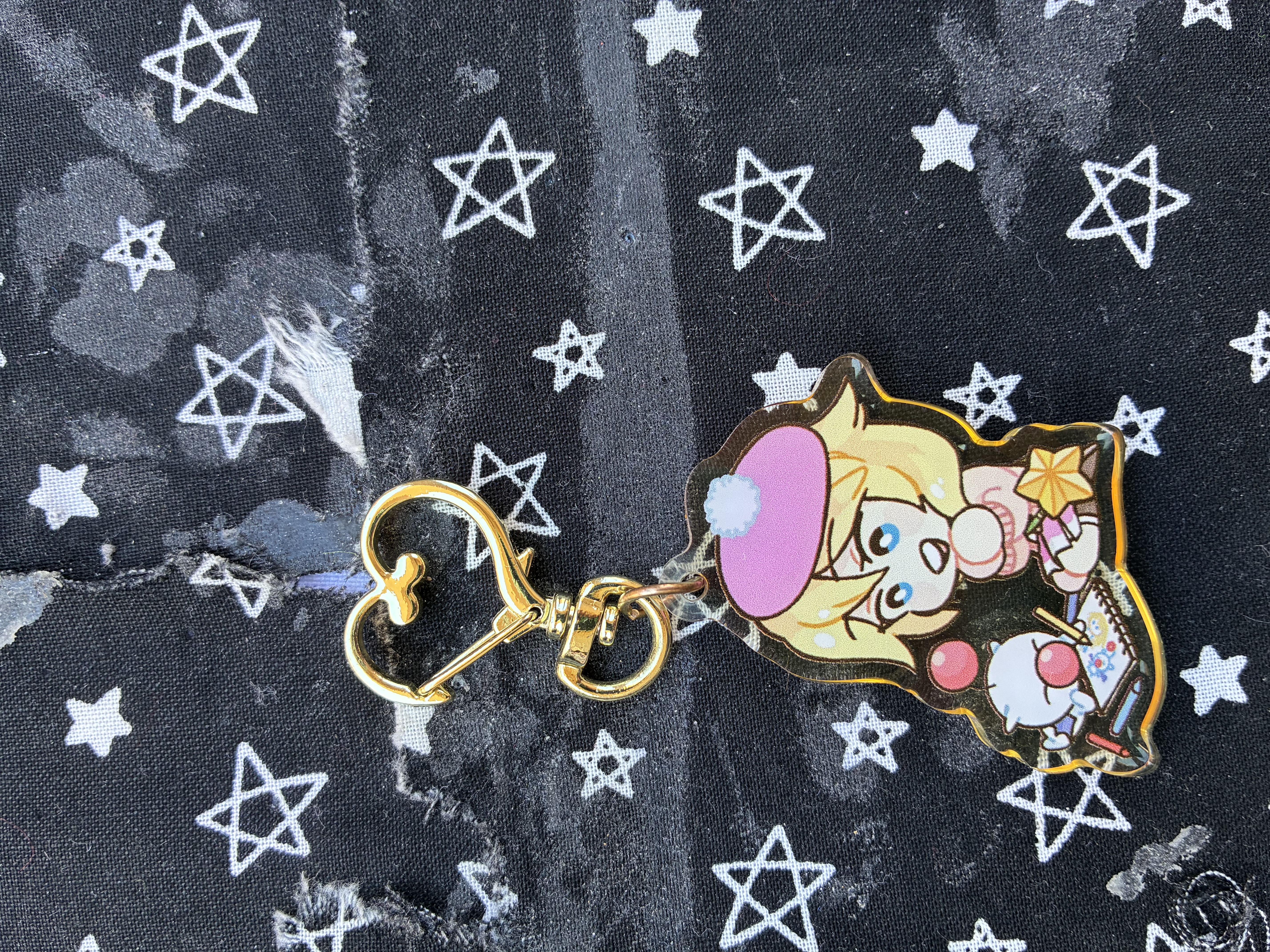 Acrylic charm of Kingdom hearts Namine in a cute outfit sitting next to a moogle who is sketching on a sketchpad.