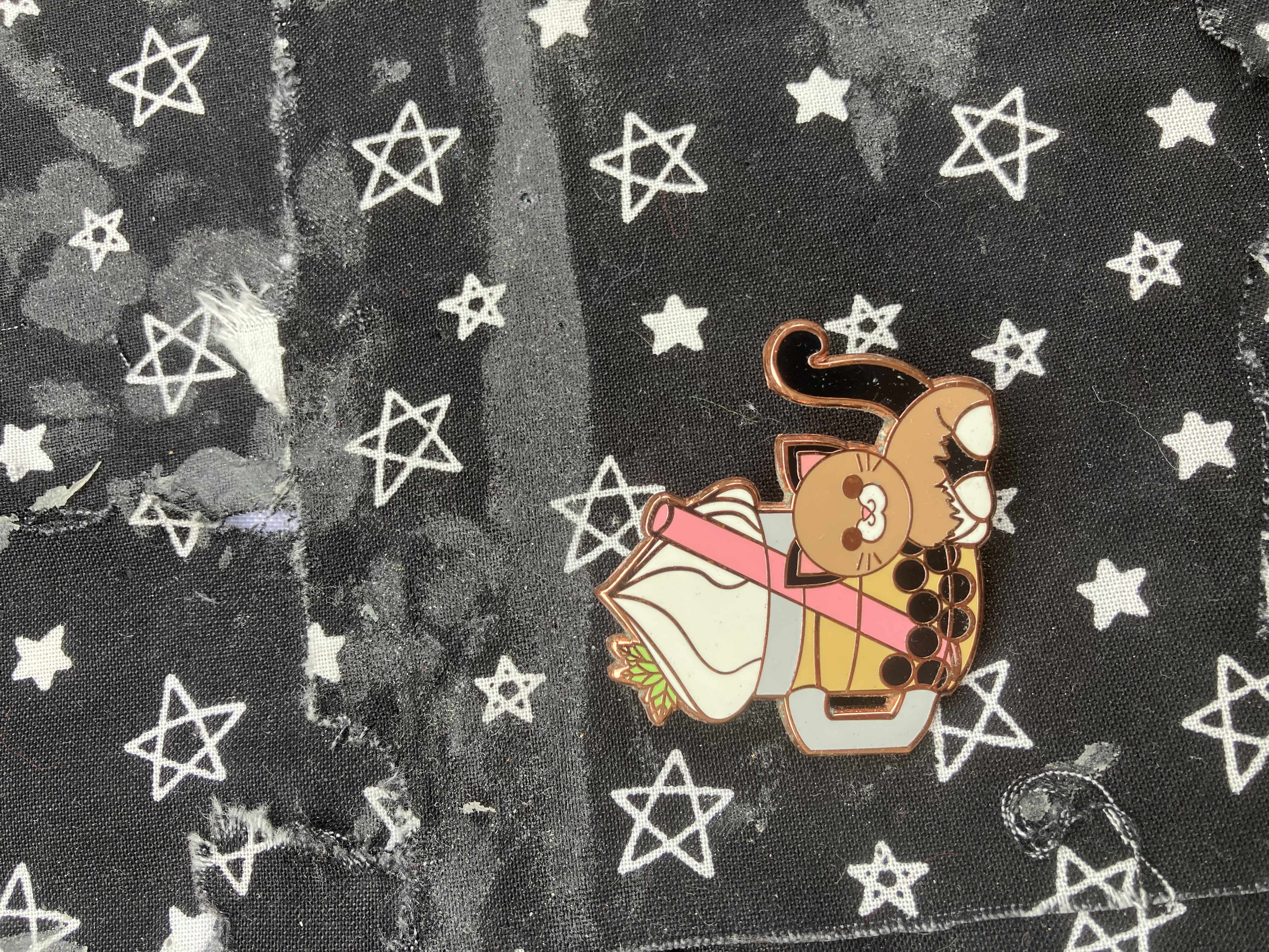 Enamel pin designed to look like a cat sitting next to a cup of bubble tea.