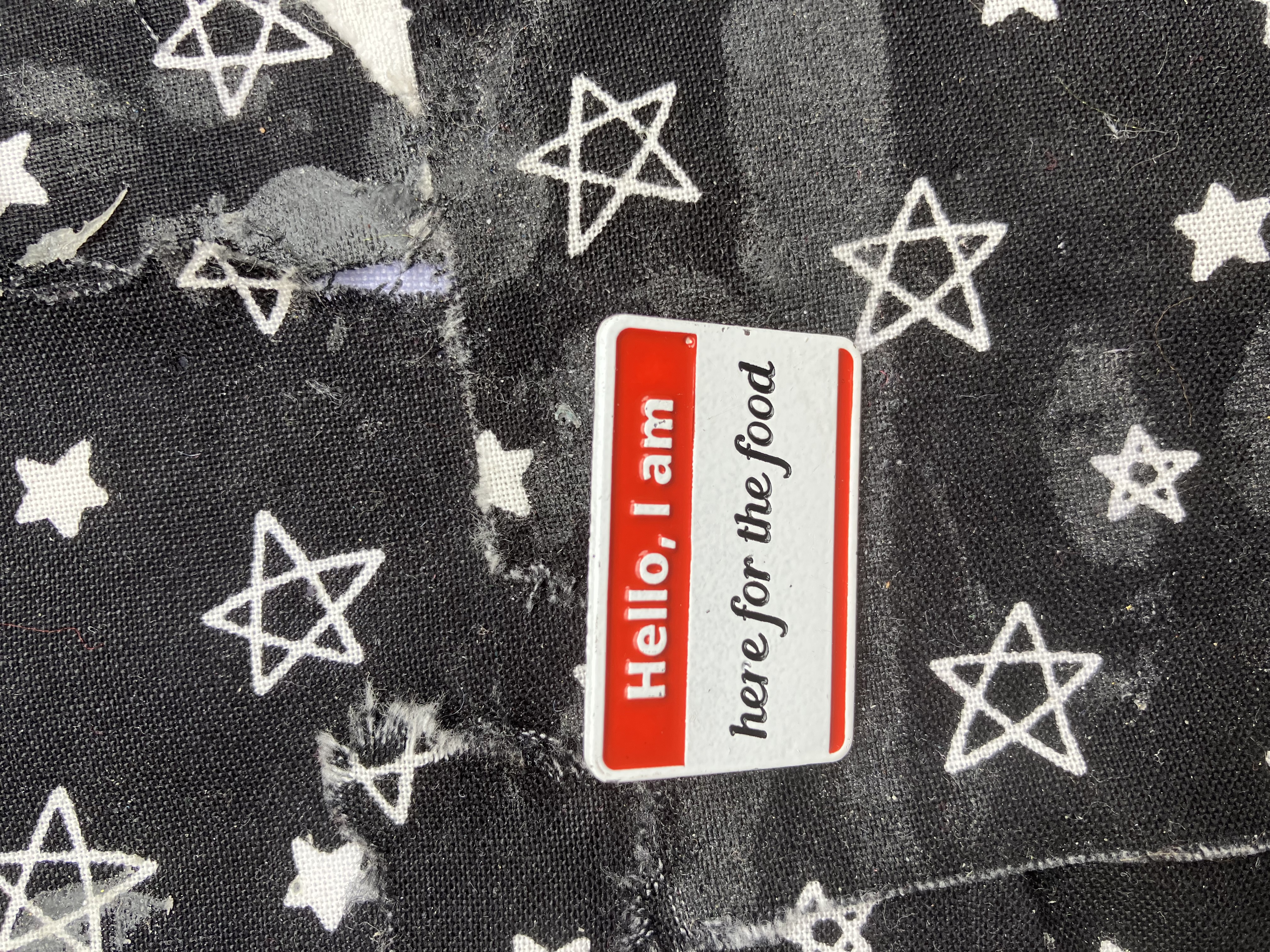 Enamel pin style nametag that reads hello I am, here for the food.
