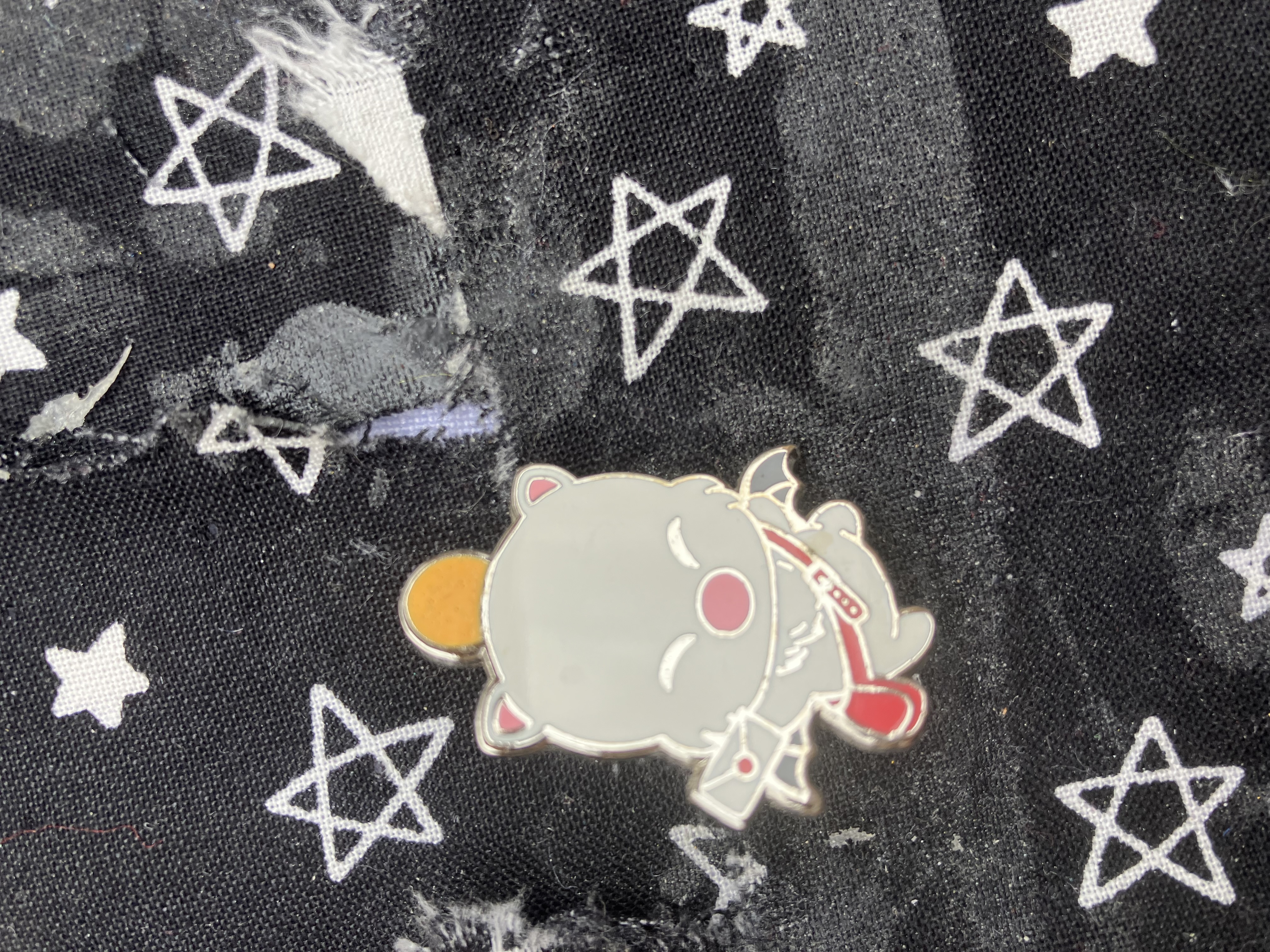 Enamel pin of a moogle wearing a satchel and holding a letter.