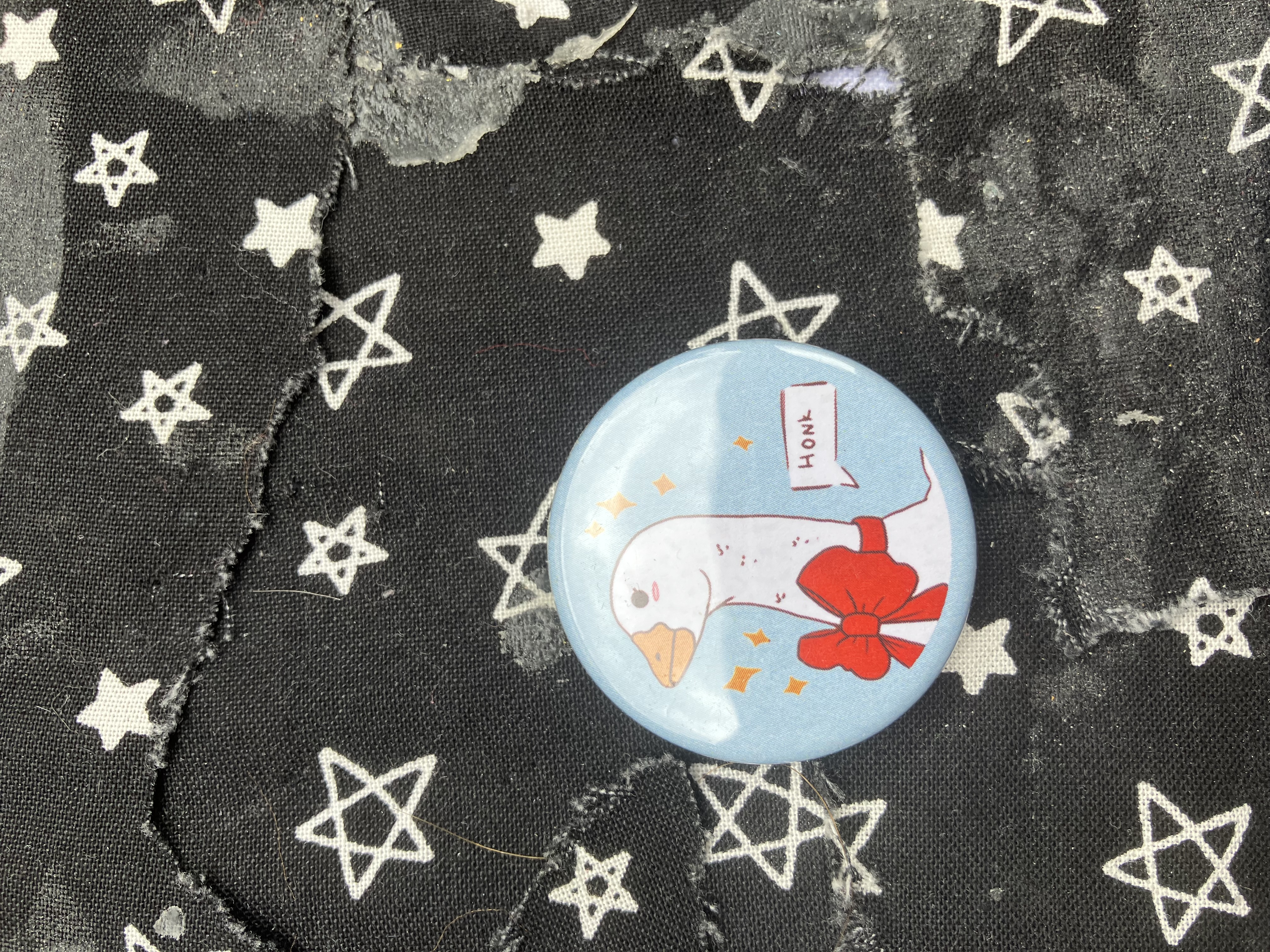 Button of a goose wearing a bow with a speak bubble that says honk.
