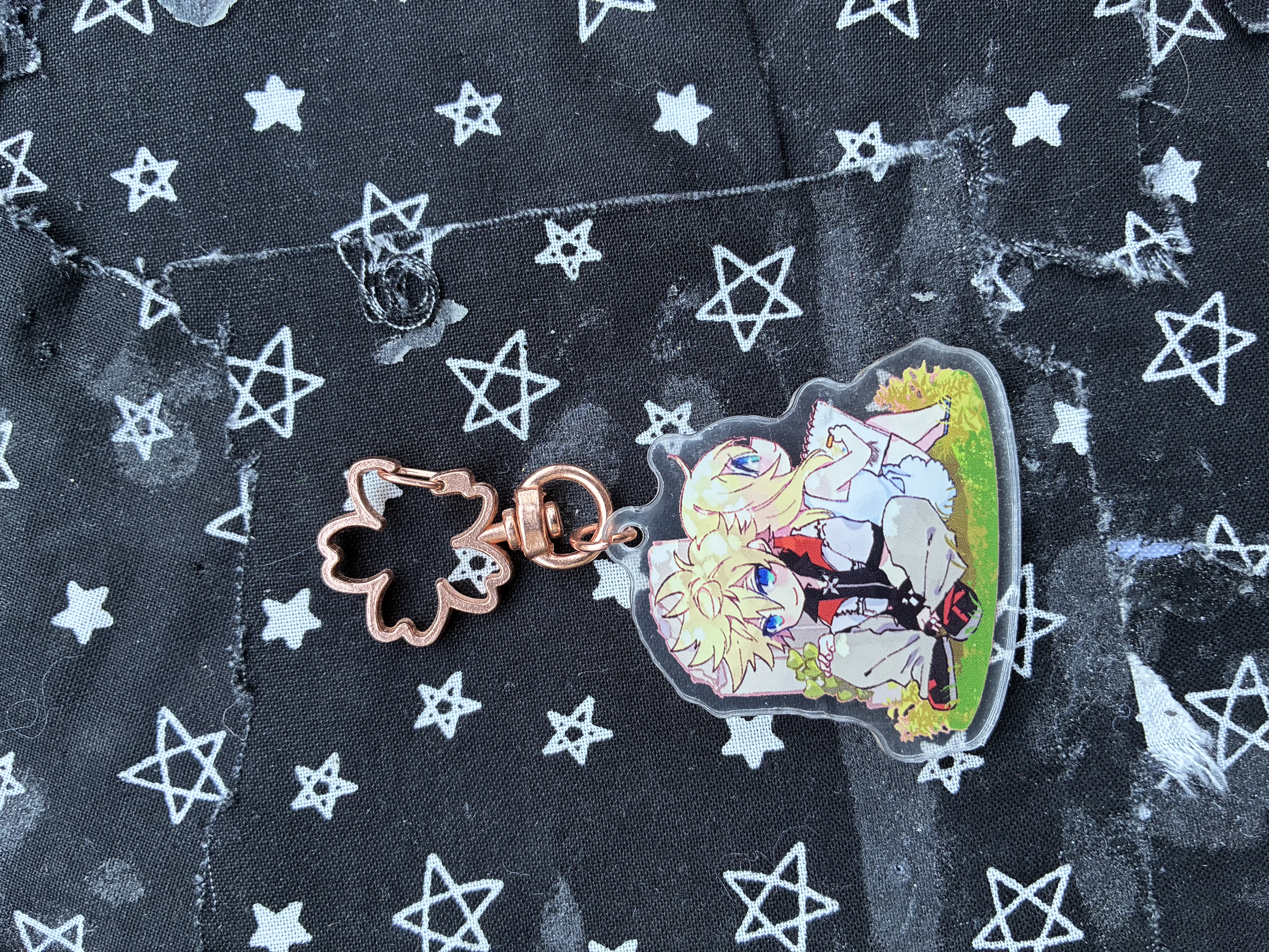 Acrylic charm of Kingdom hearts Roxas and Namine sitting by back to back with smiles on their faces.