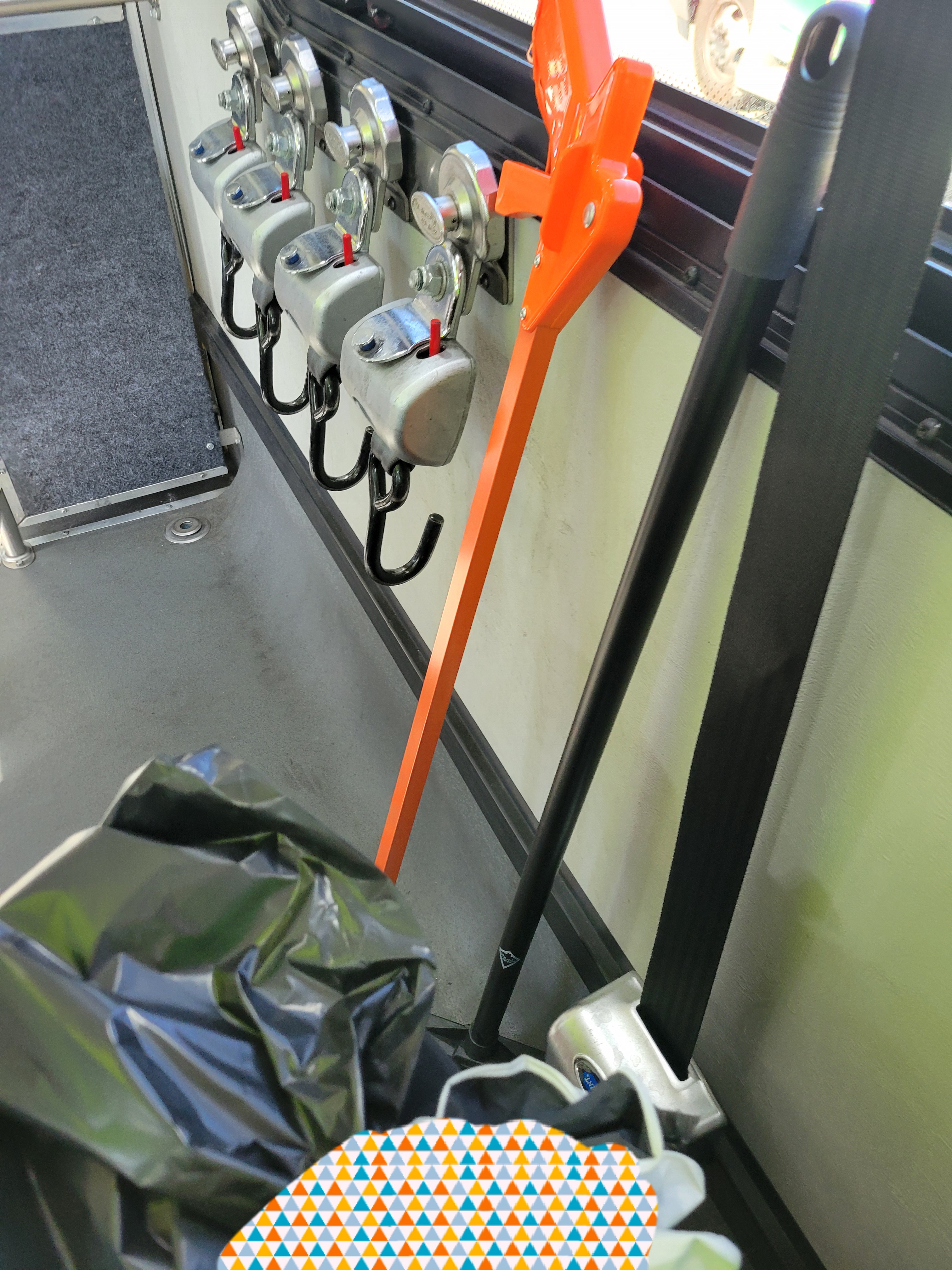 Trash picker leaned on bus's window with gloves and trash bag in frame.