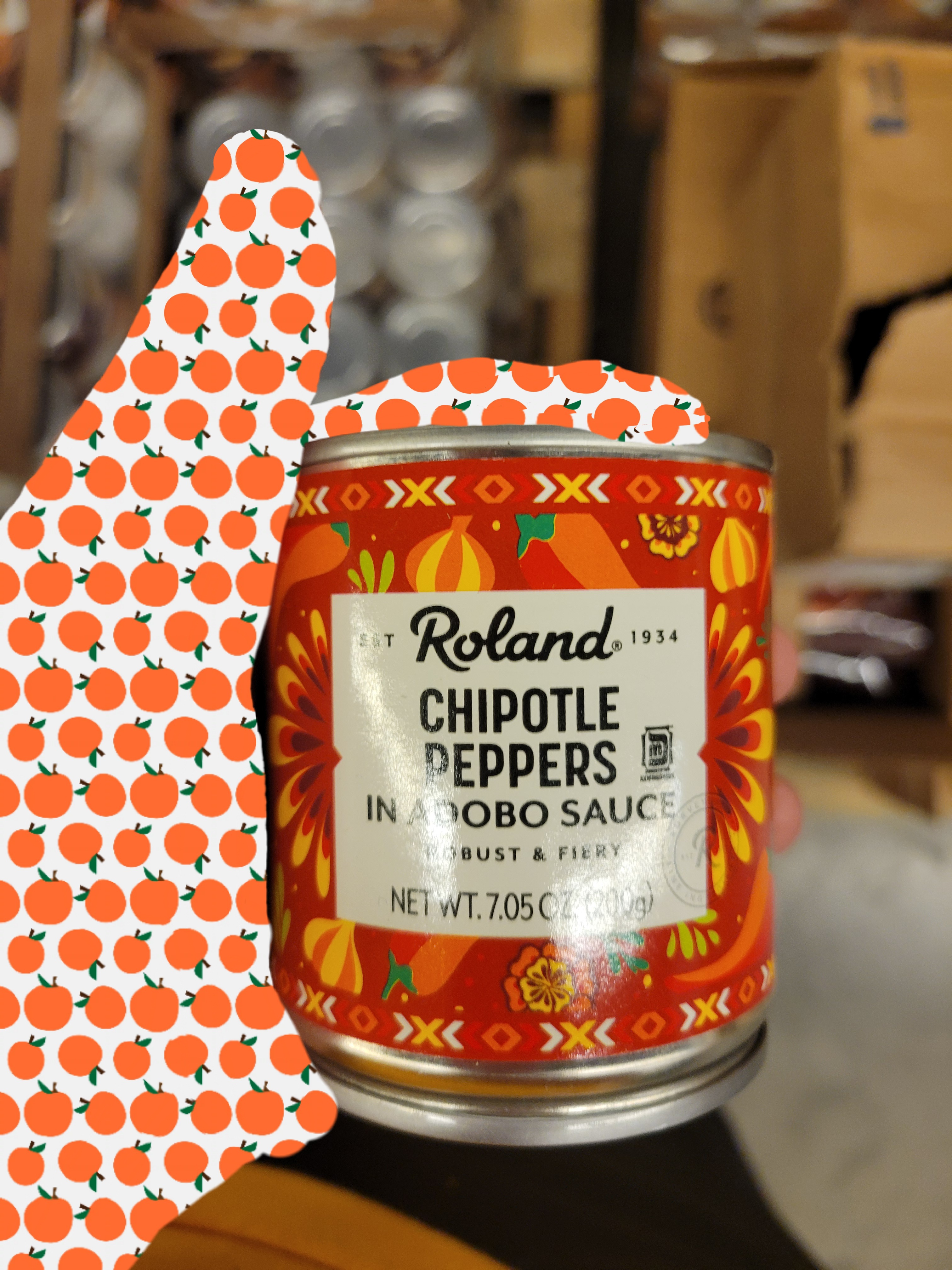 Hand holds a can of chipotle peppers in adobo sauce.