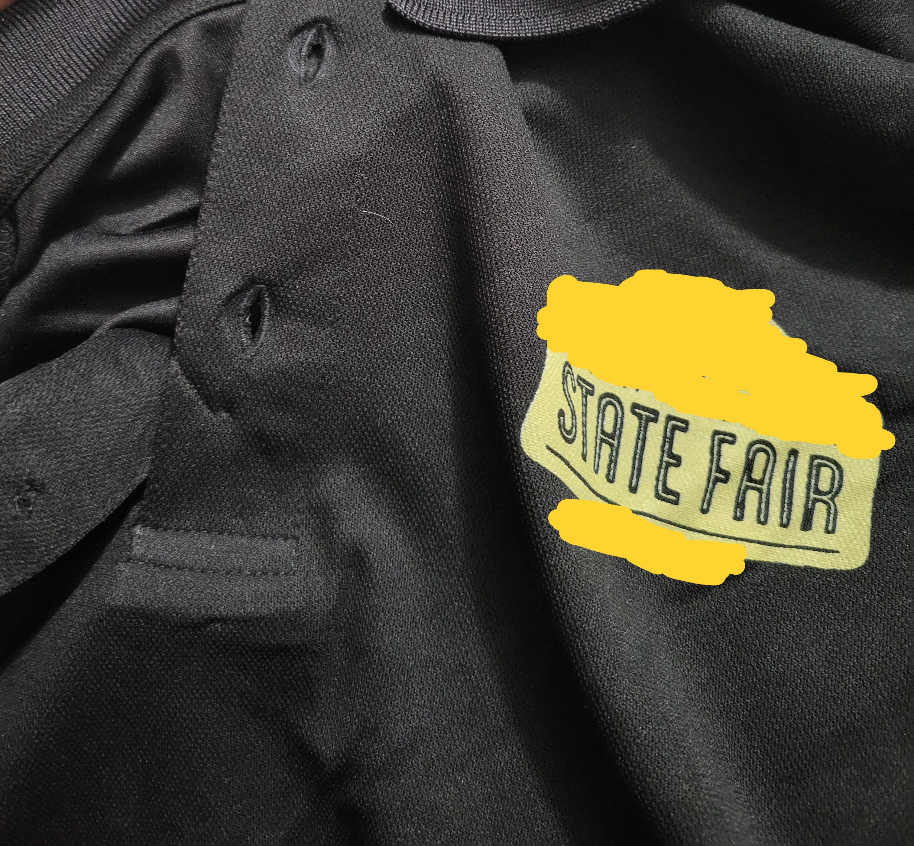 Black polo shirt with yellow lettering that says state fair.