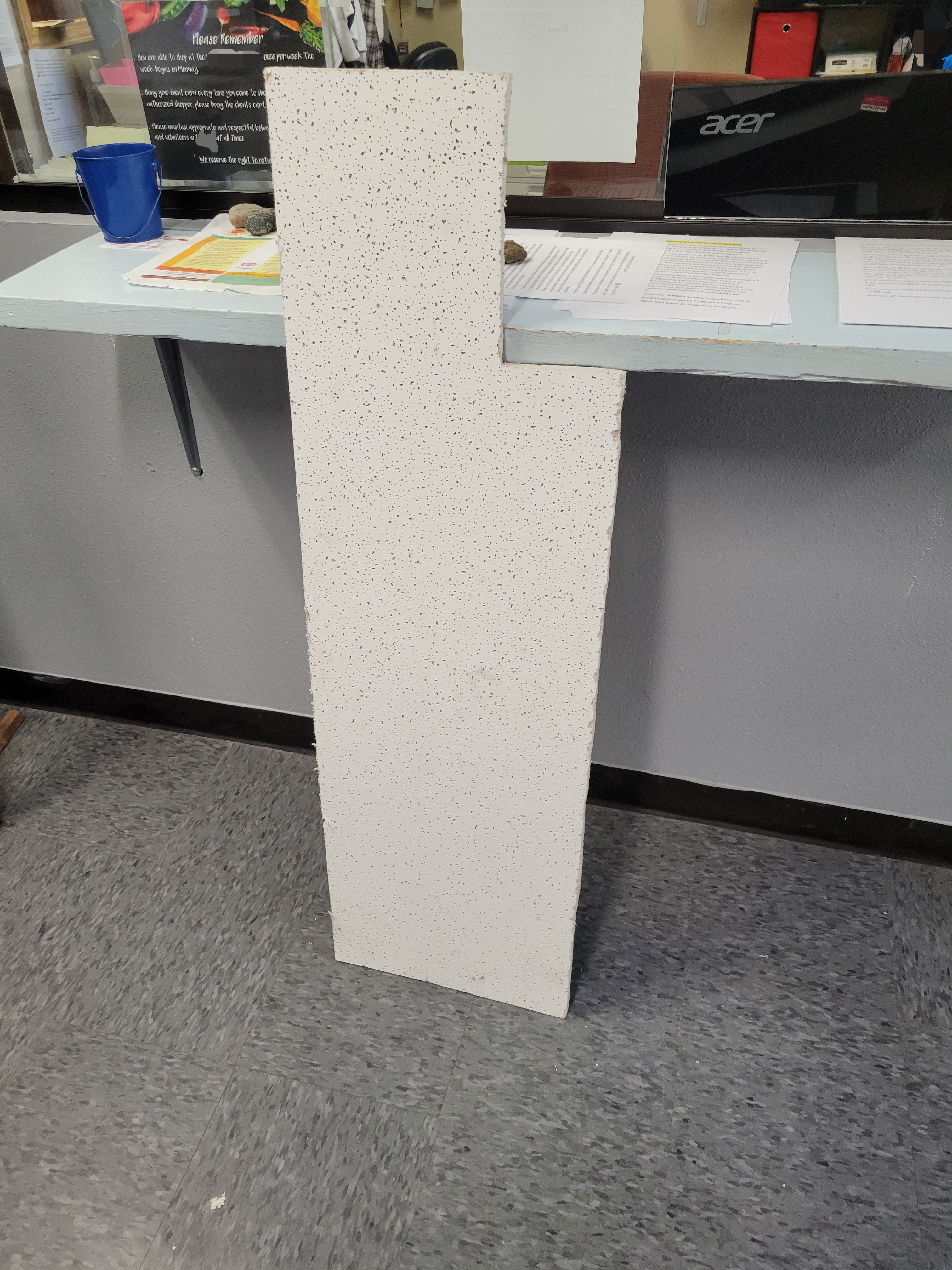 Ceiling panel on the ground in front of a check in window with a sign about the rules of the food pantry's.