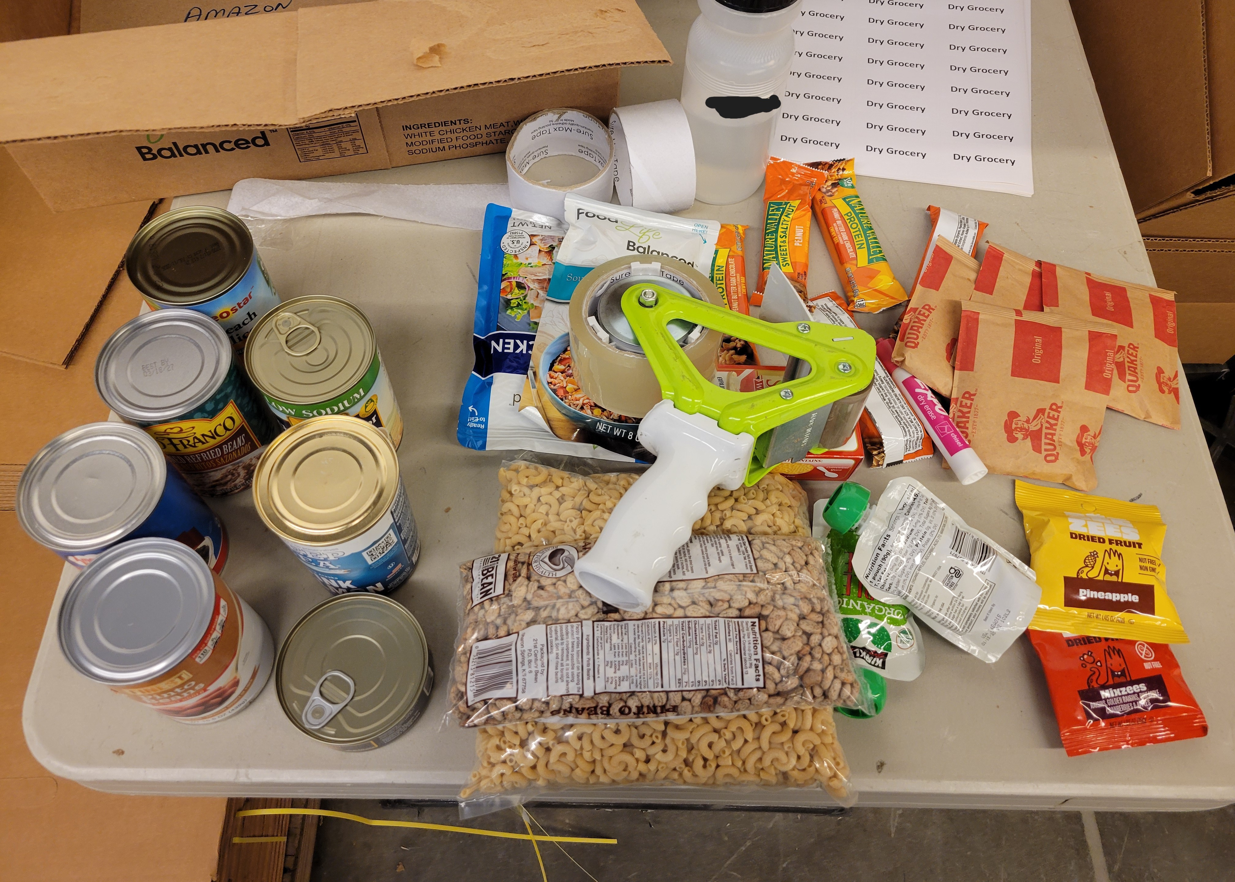 Various dry goods on a table with a tape gun on top of some.