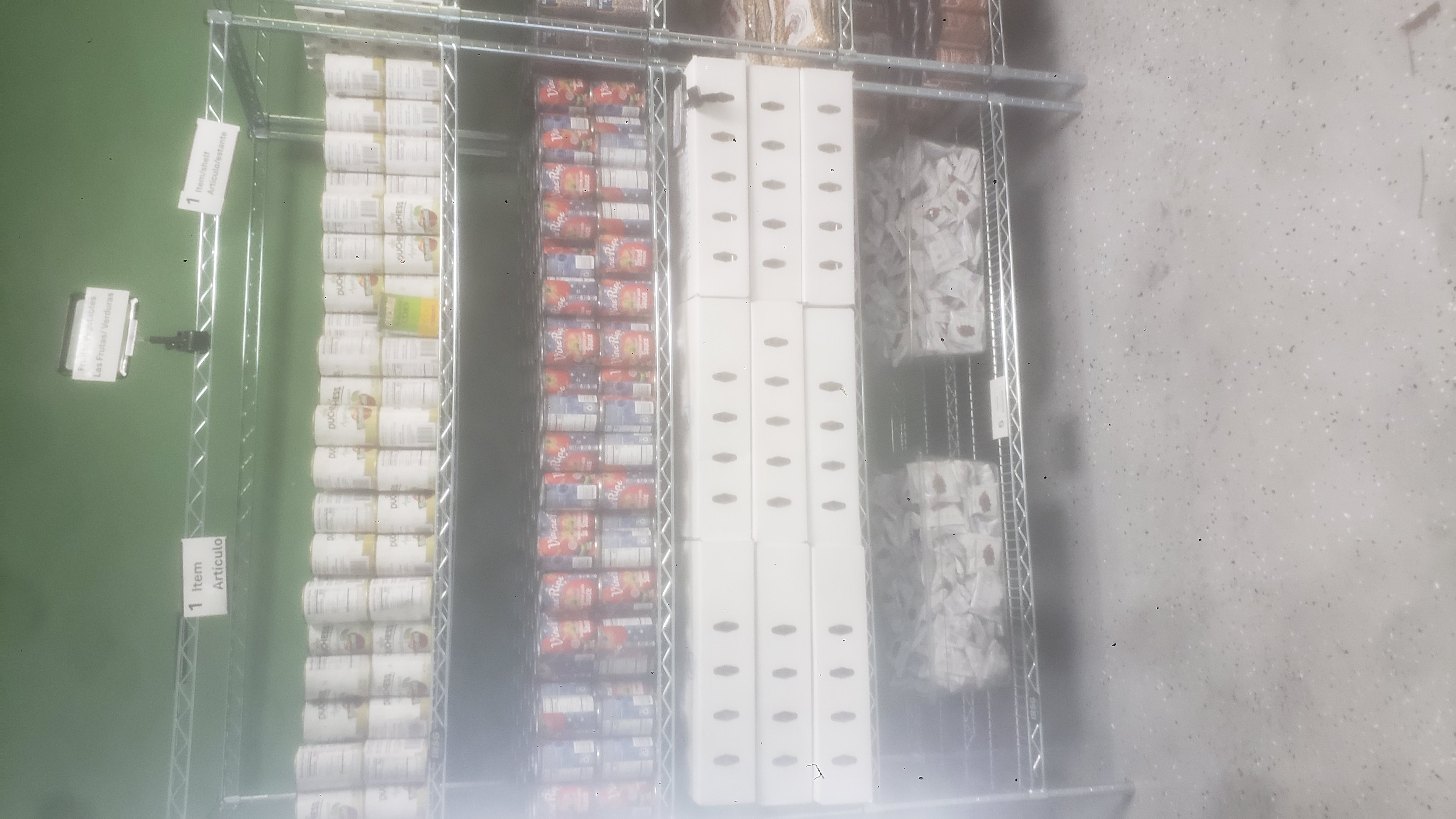 Cans of tomato sauce, cans of applesauce, boxes filled with cups of dutch apple, and packets of dried cranberries on a shelf.