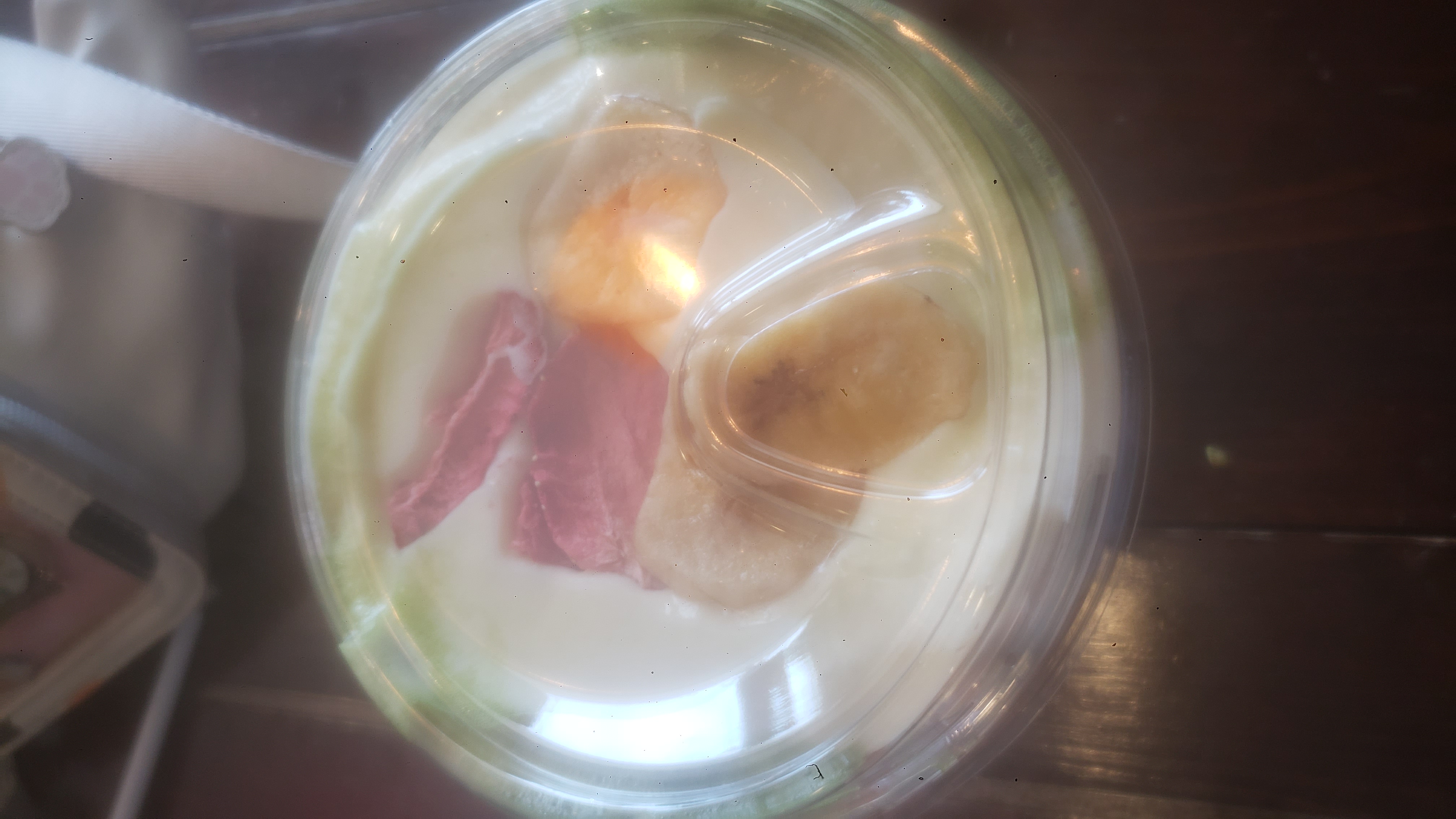 Top of a to go cup of matcha with dried strawberry and banana.