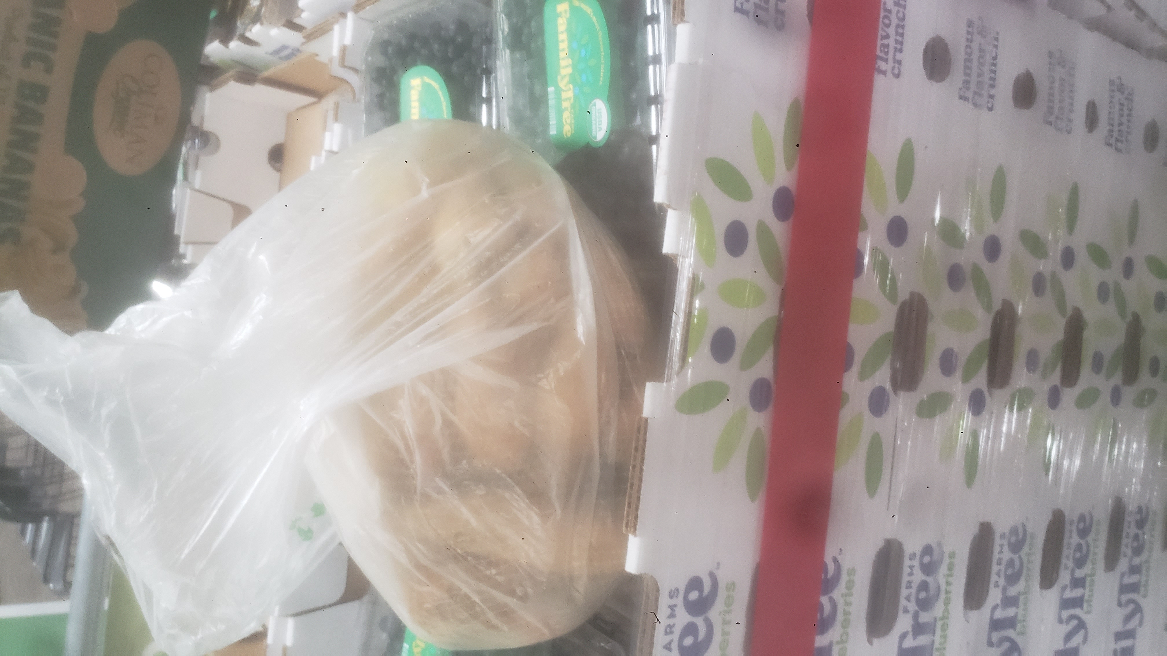Bread rolls in plastic next to containers of blueberries in a tray.