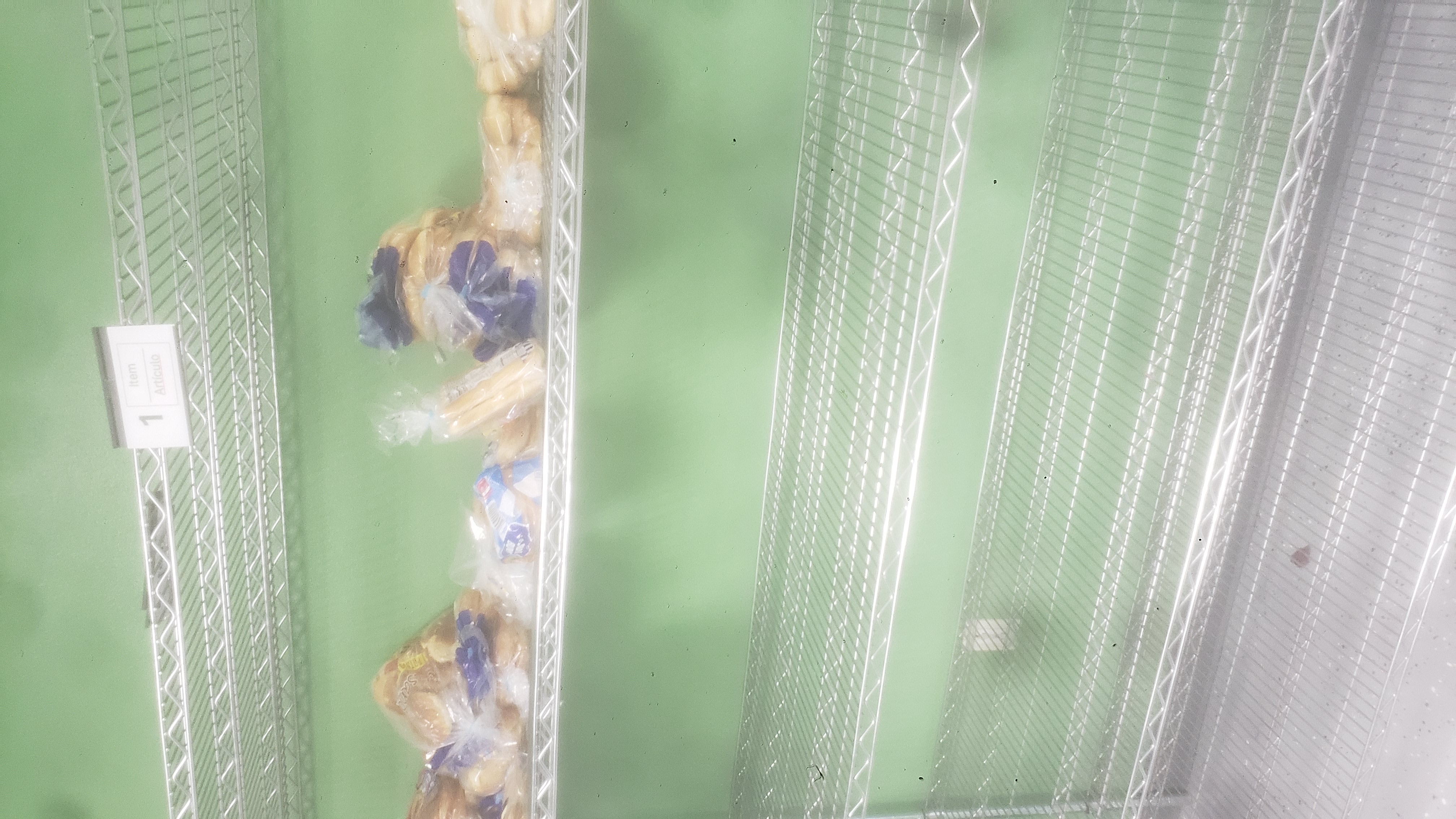 Various breads on the second rack of a shelf.
