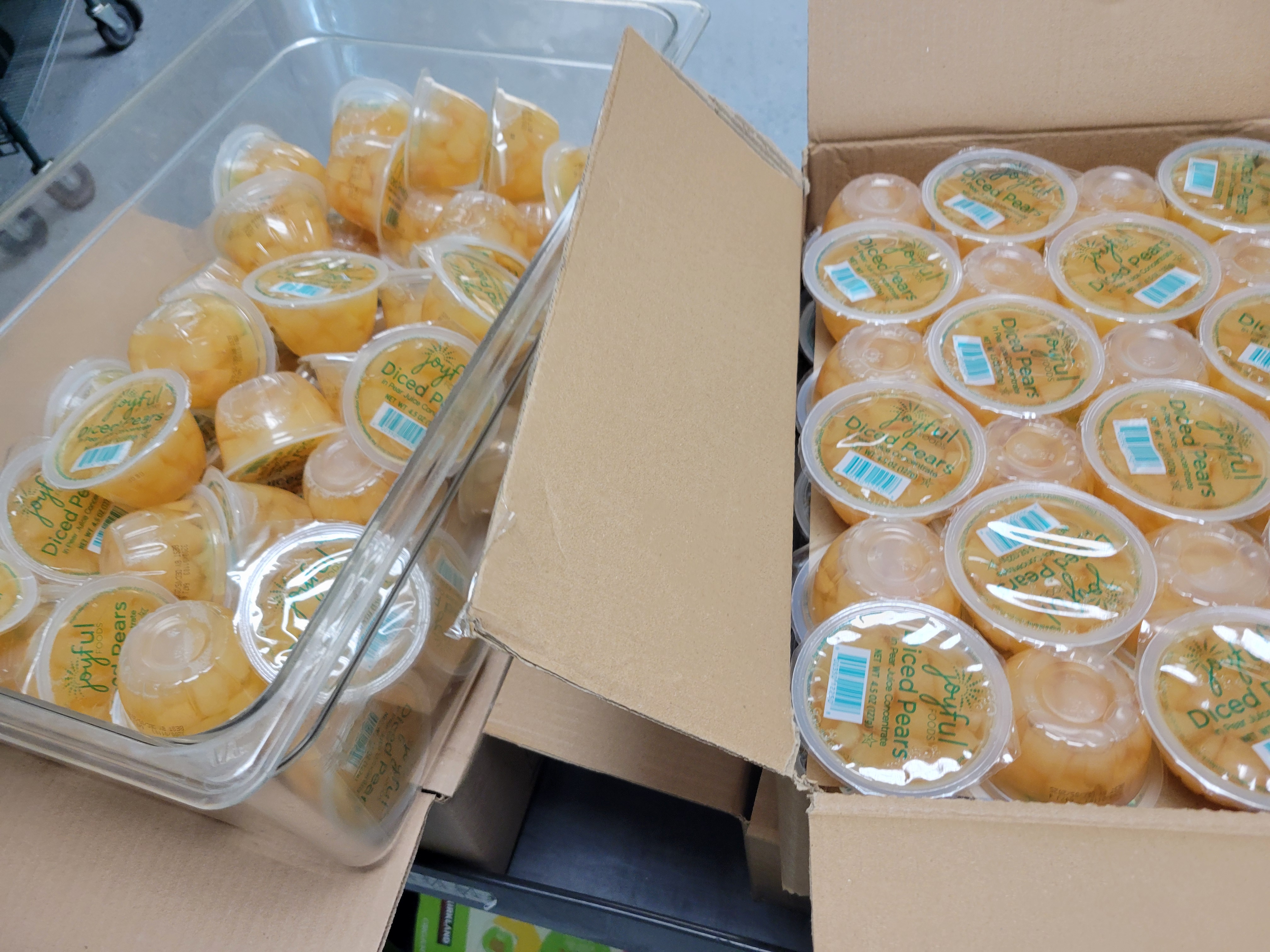 Plastic tub and box of cups of diced pears on top of boxes.