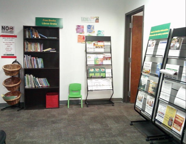 Racks of resources flyers on one side of the room and a bookcase plus 3 tier basket display case filled with books on the other.