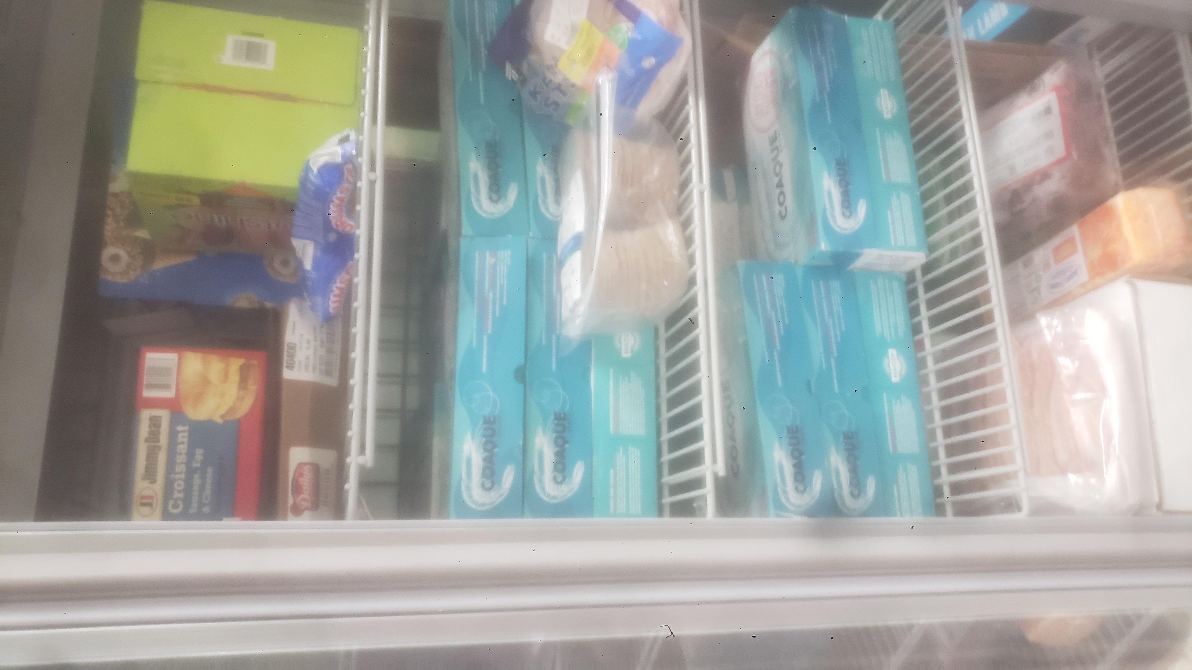 Assorted frozen items such as block of cheese, box of breakdfast sandwiches, and boxes of shrimp.