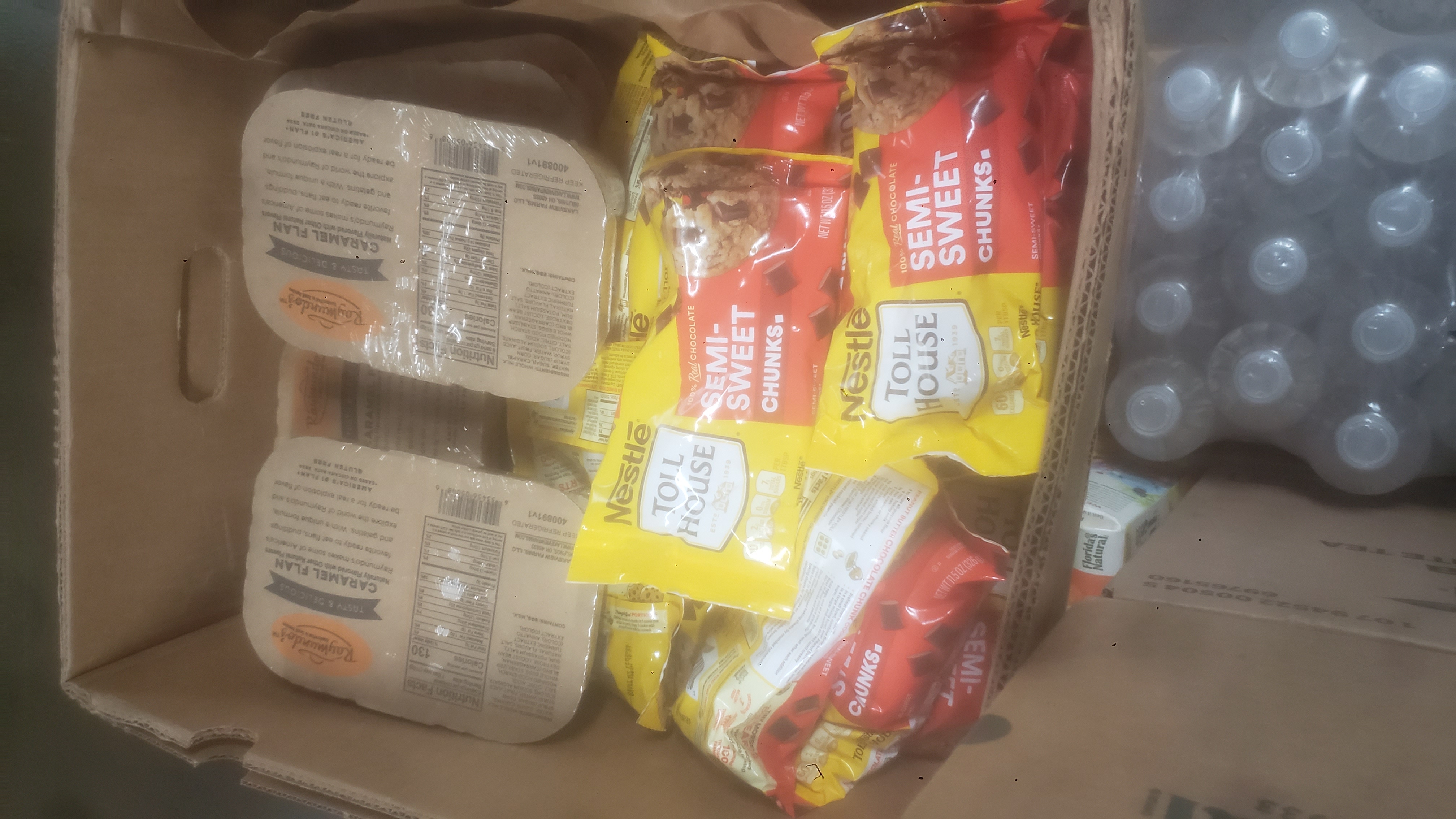 Bags of semi-sweet chocolate chunks, and cases of caramel flan in a banana box.