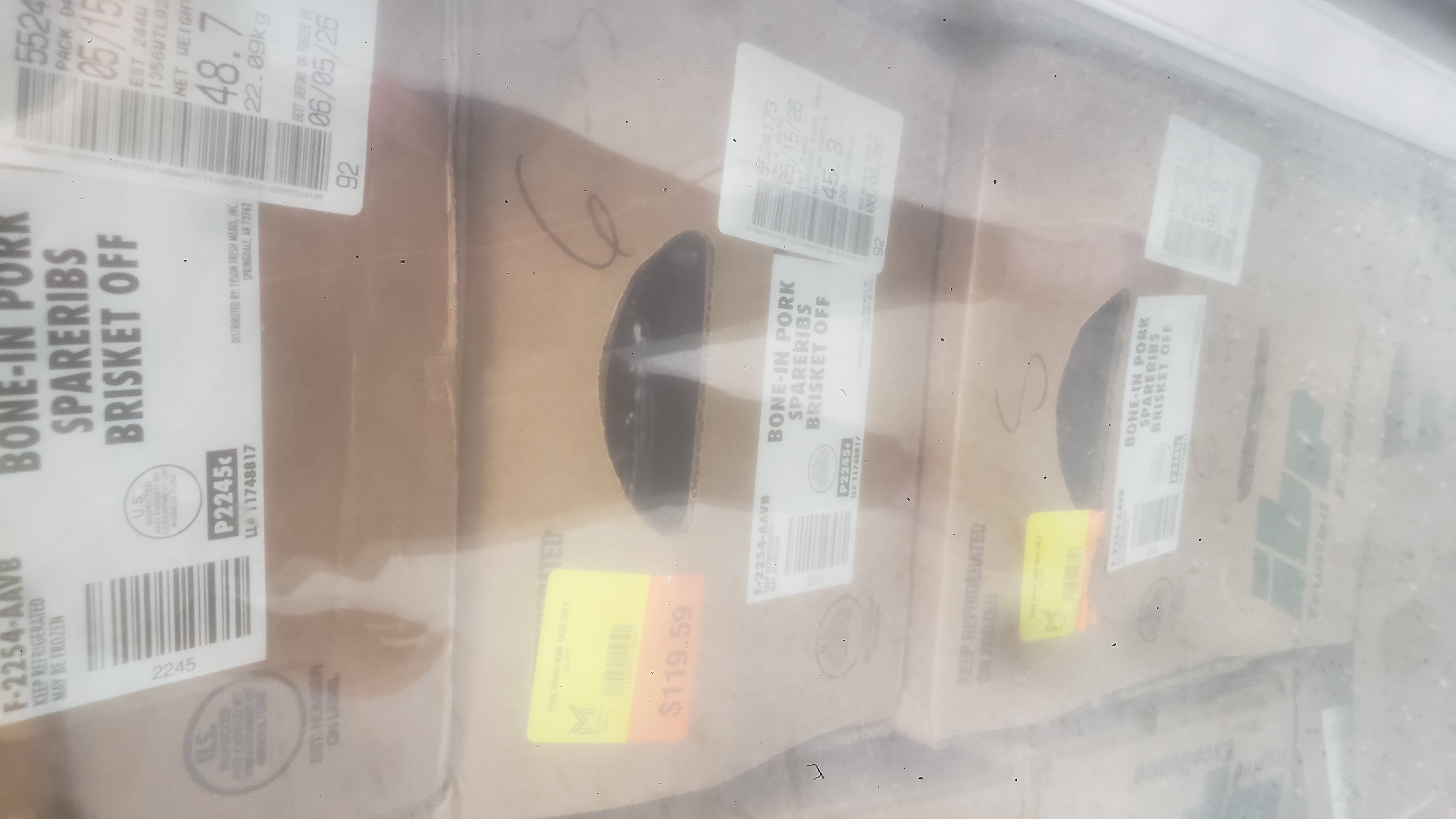 Stacked cardboard boxes of bone-in pork spareribs brisket off.