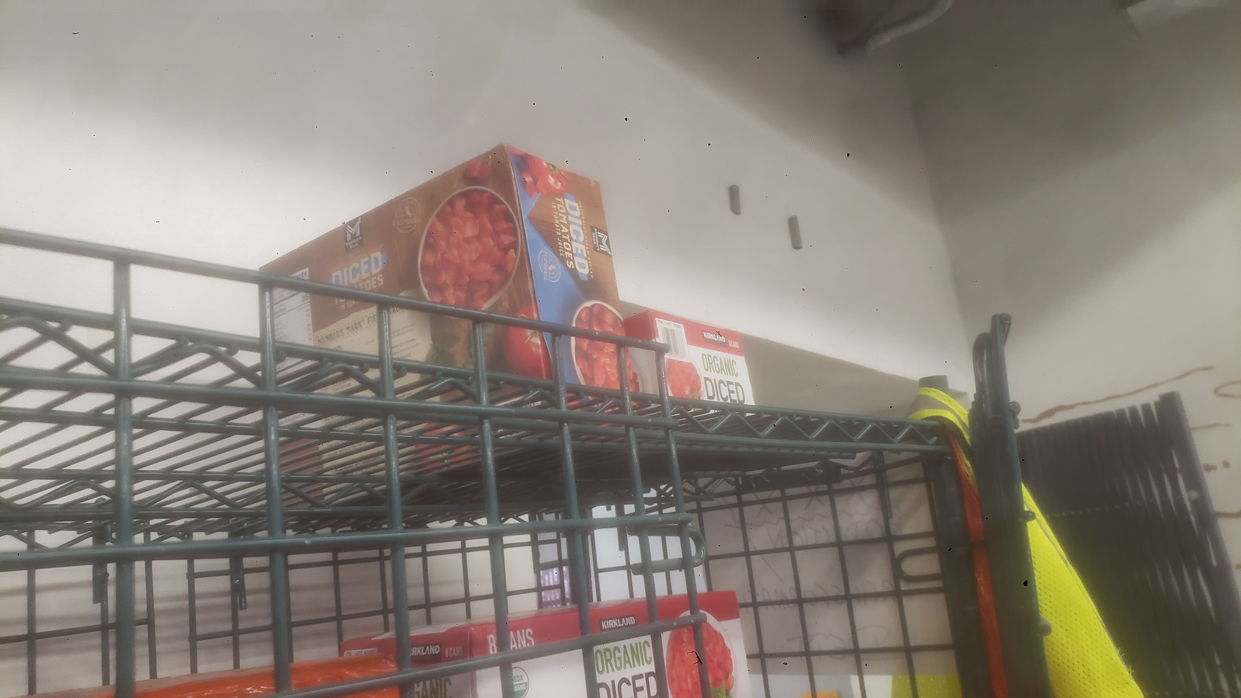Boxes of diced tomatoes in inside and on top of cage shelf.