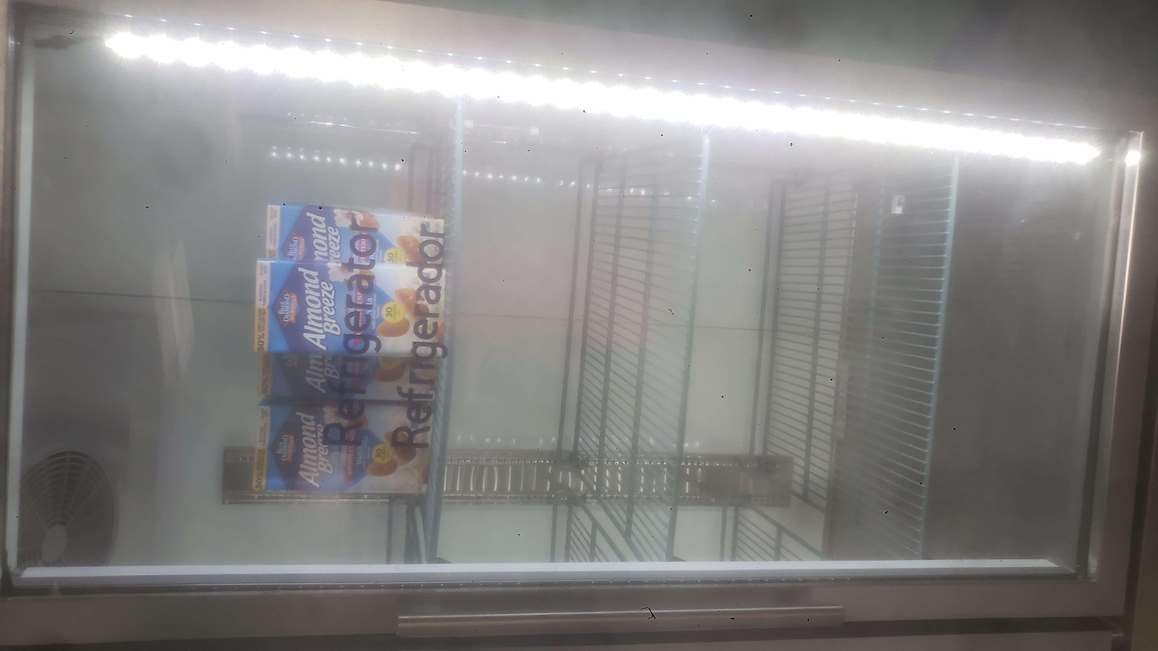 Cartons of almond milks on the top shelf of a fridge