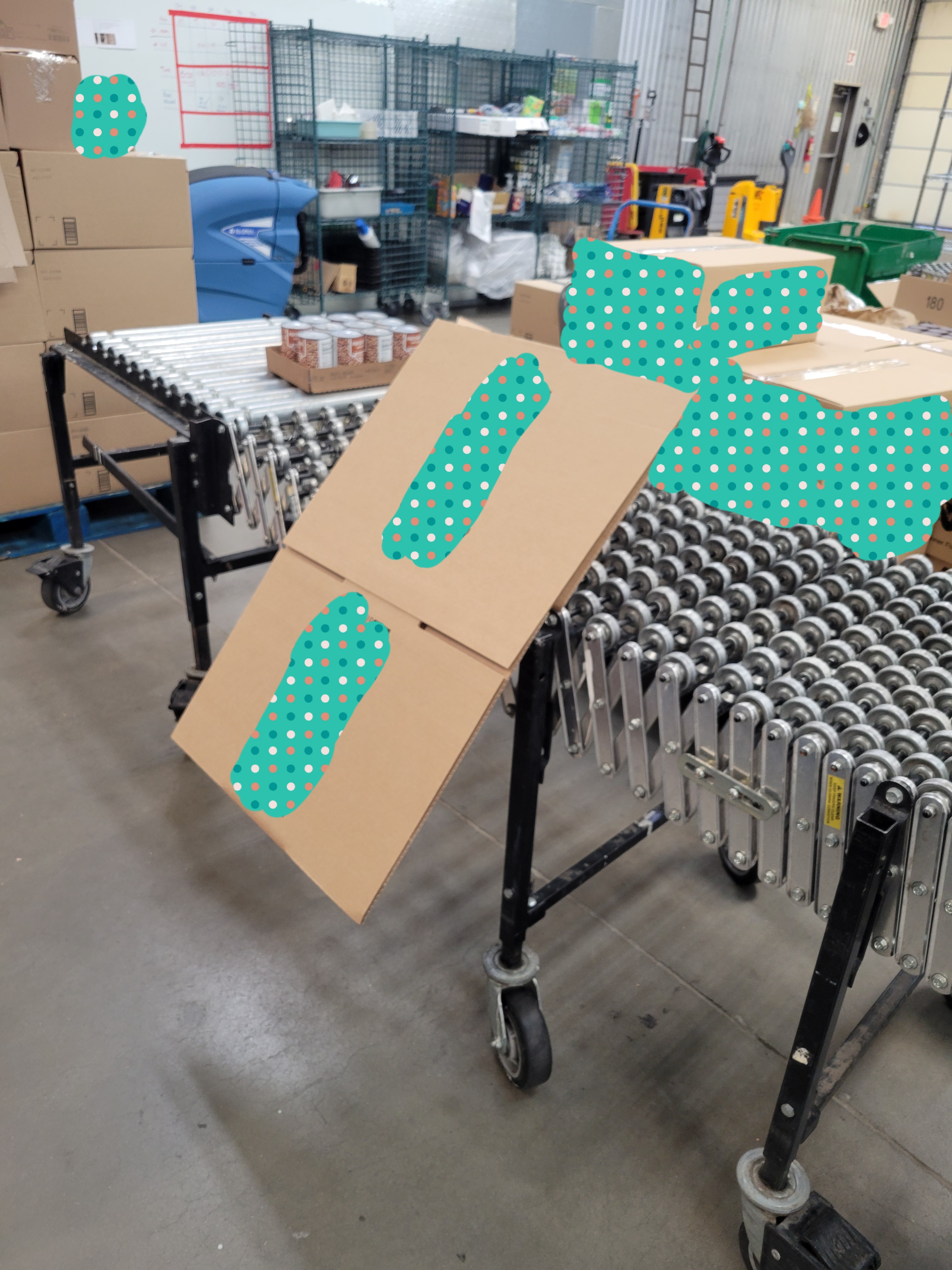 Cardboard box hangs on the side of a conveyor belt next to cans of pinto beans.