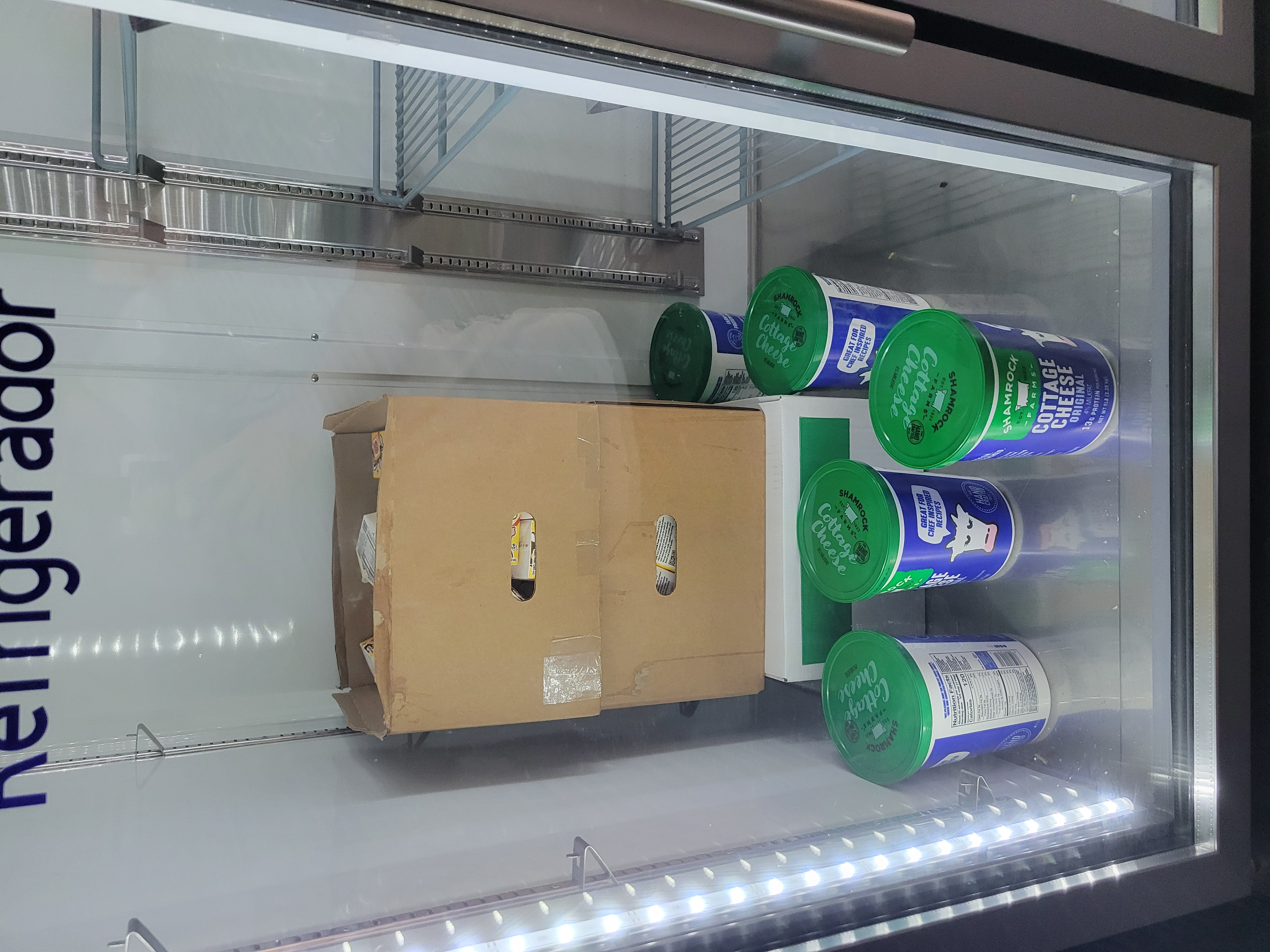 3 boxes with tubs of cottage cheese around it in a fridge.