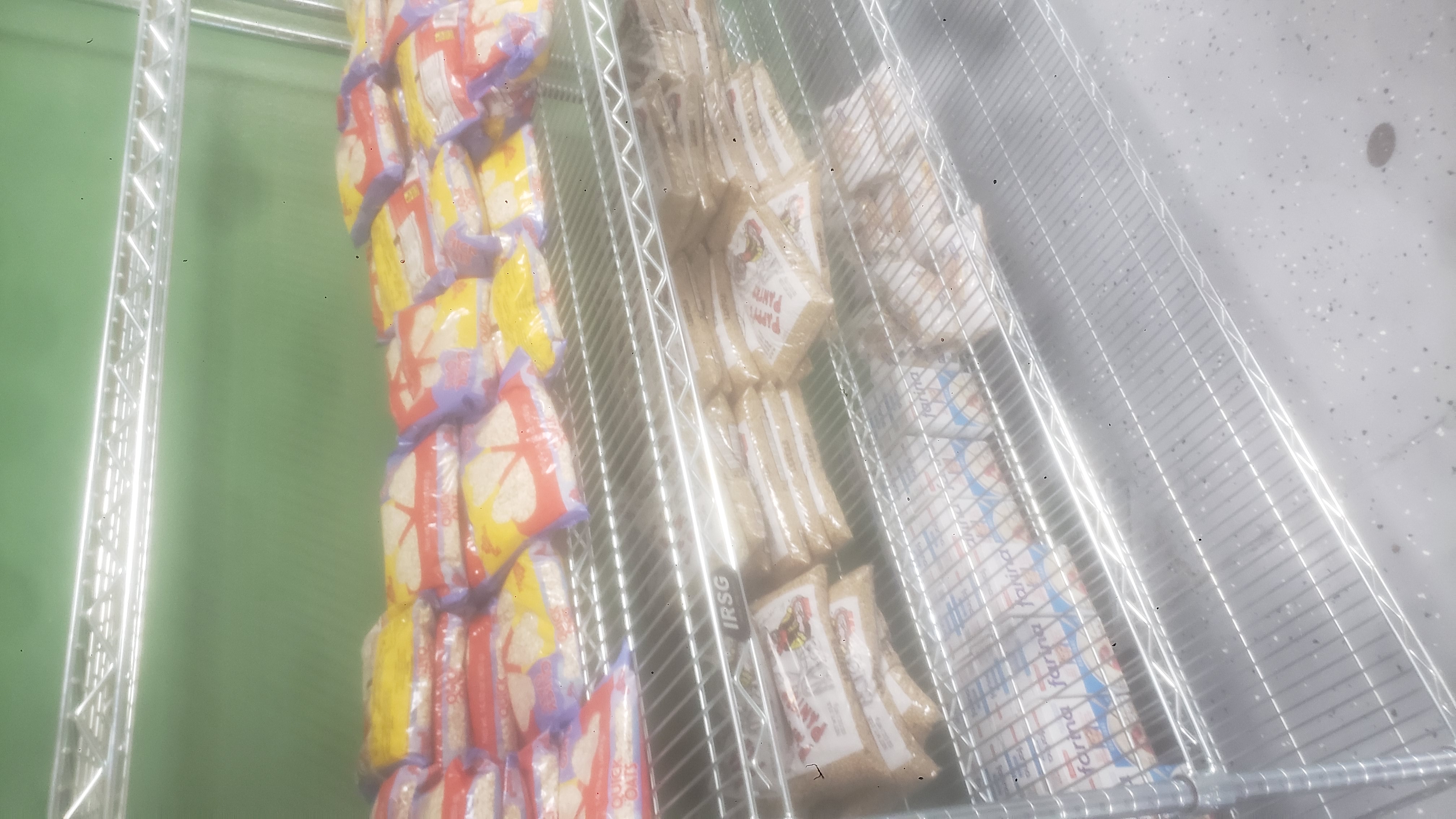 Bags of oats, bags of lentils, bags of brown rice, and boxes of farina on a four tier shelf.