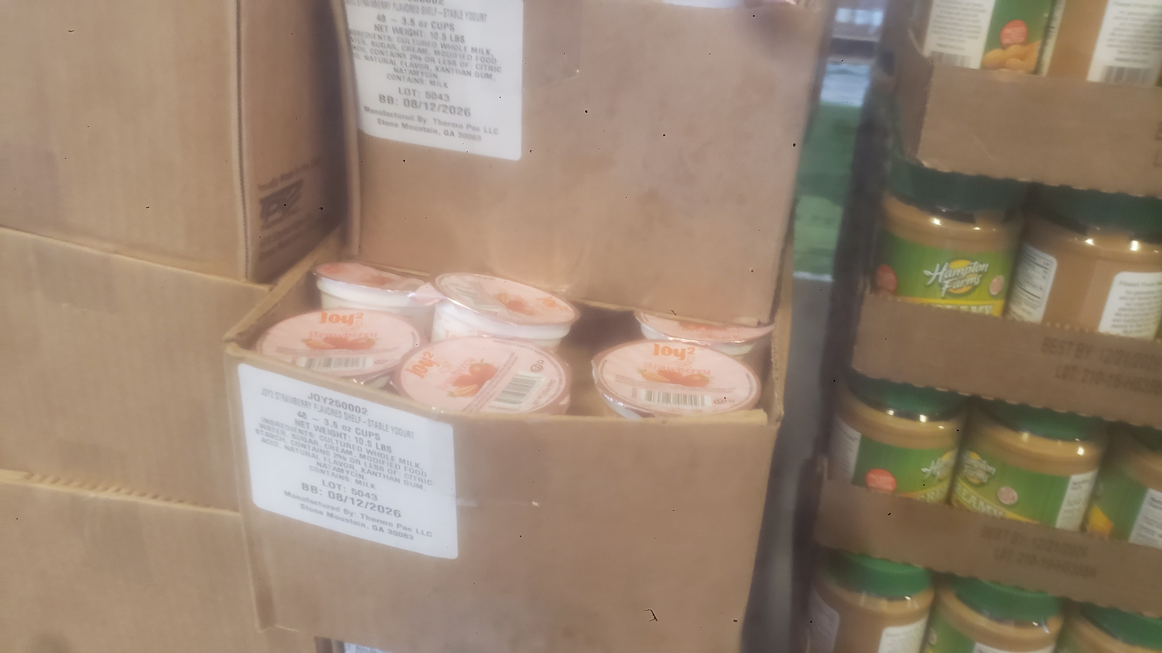 Boxes filled with cups of yogurt next to trays of jars of peanut butter.