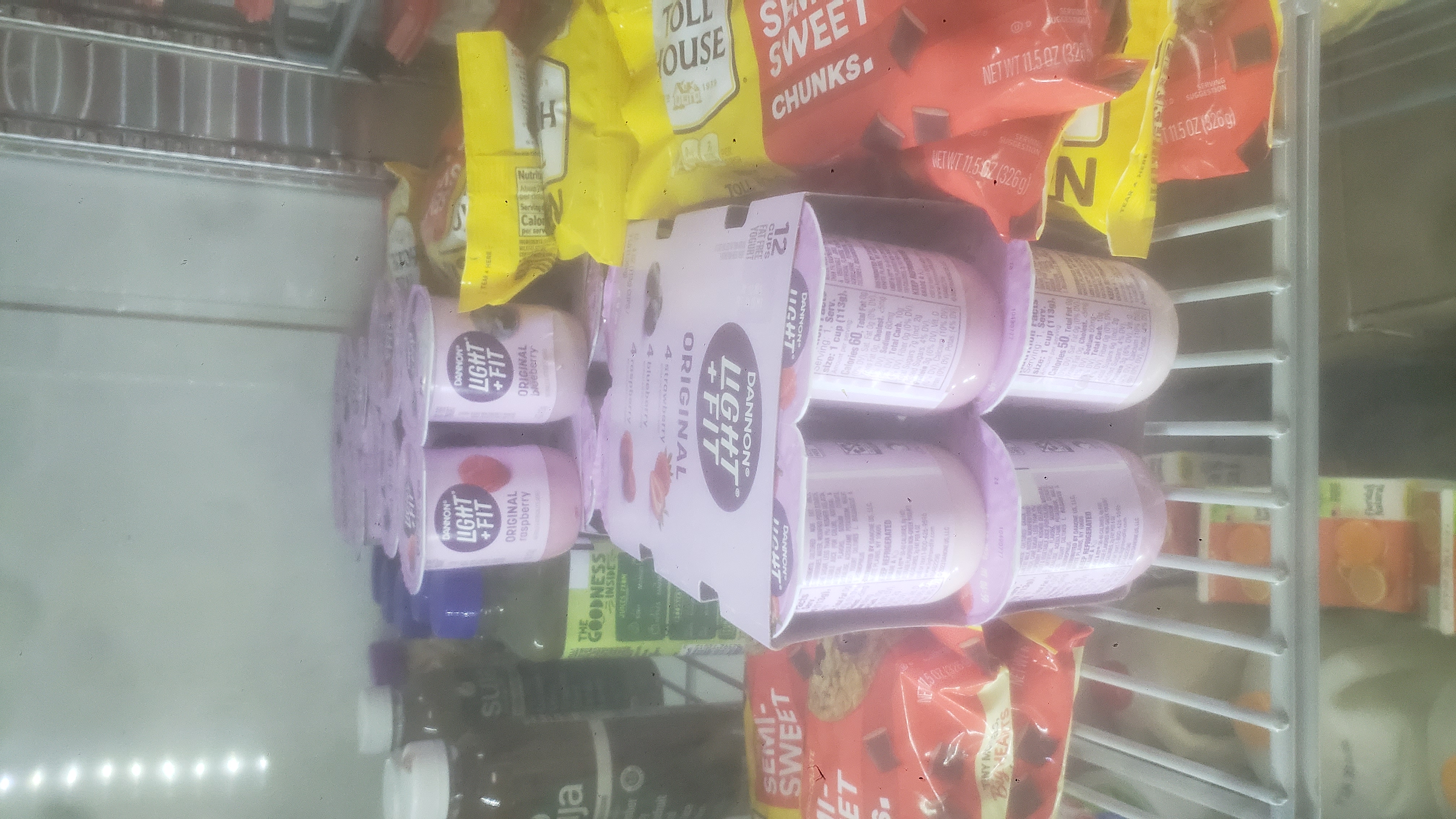 Bags of semi-sweet chocolate chucks, bottles of juice, and packs of yogurt in a fridge.