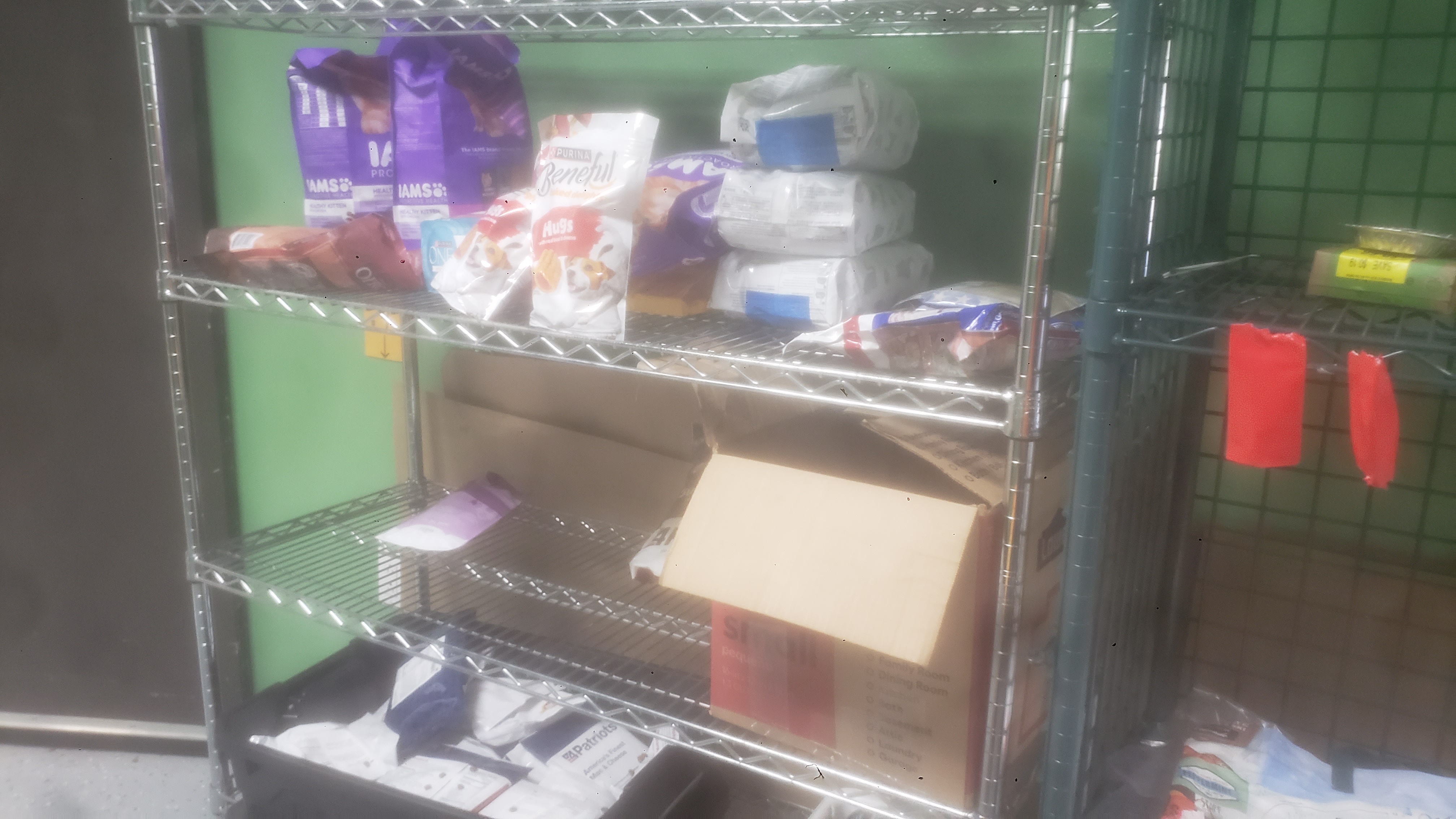 Bags of cat food, bags of dog food, bag of dog treats, and mre meals on a shelf.
