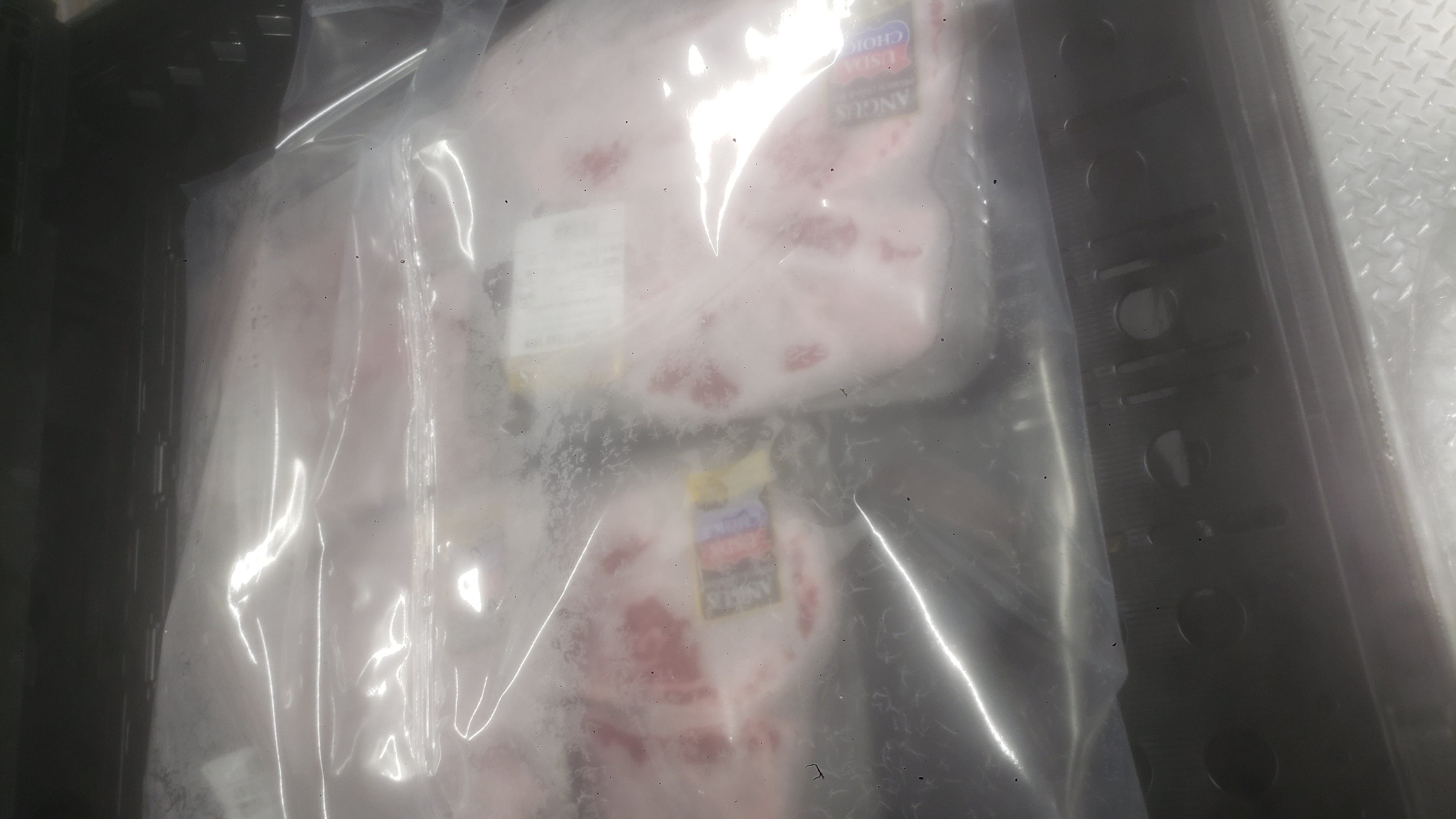 Packs of thin-cut Angus New York Strip steak covered in plastic.