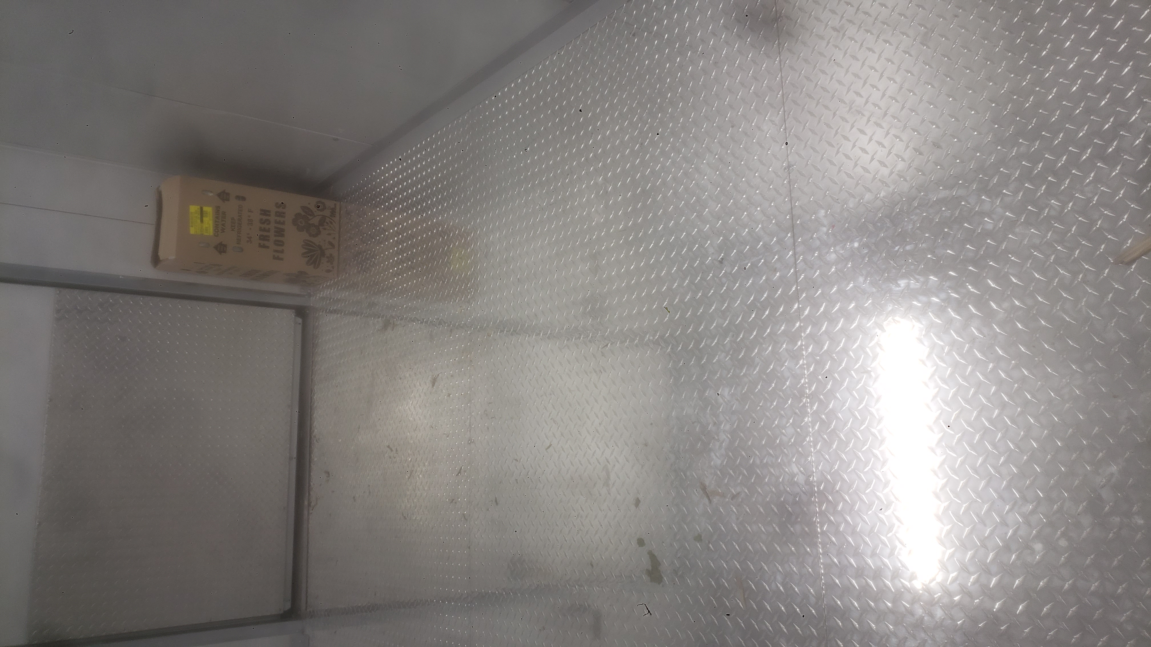 Cardboard box of flowers in a empty fridge box unit.