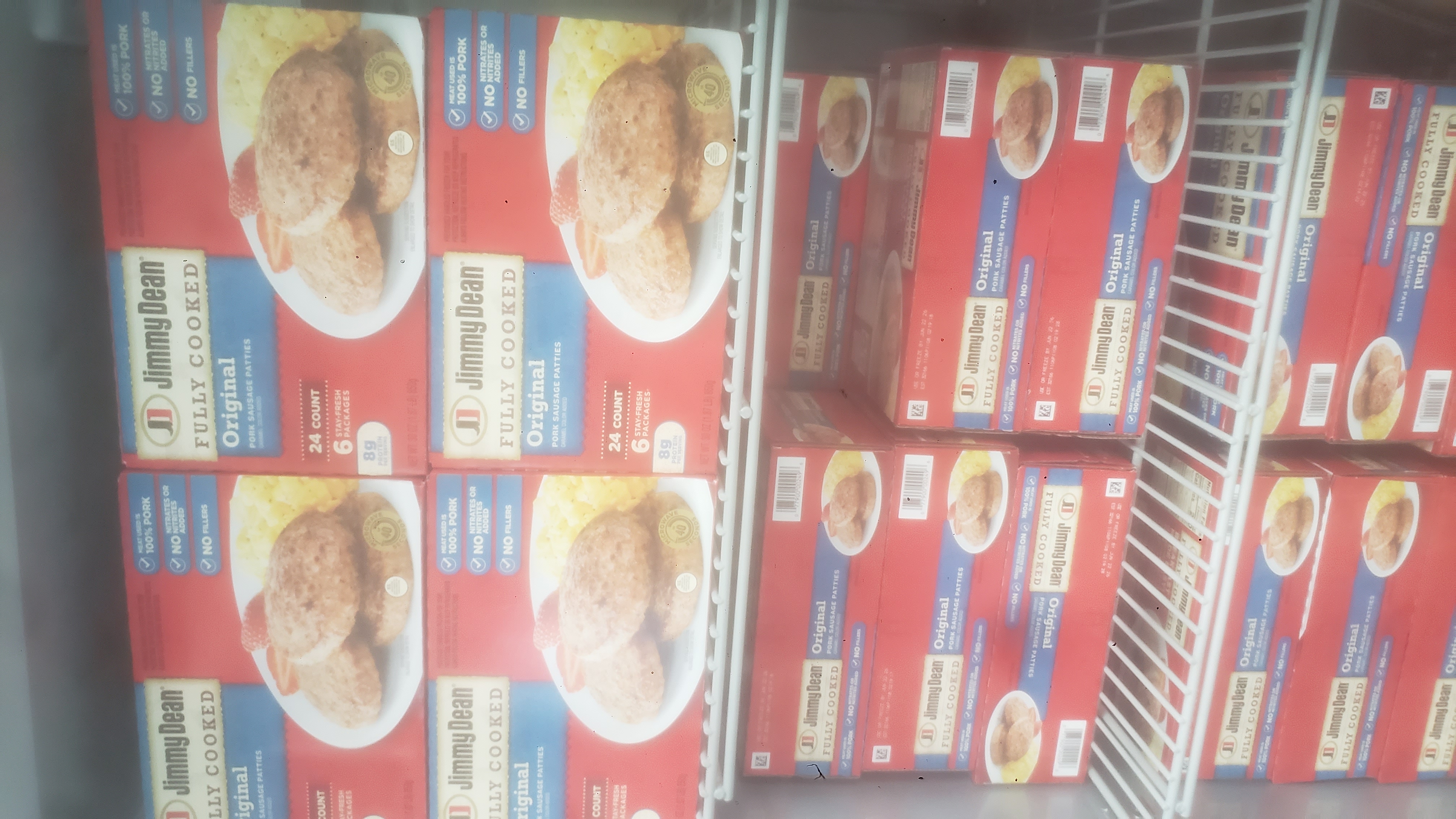 Fully cooked pork sausage patties boxes on shelves of a fridge.