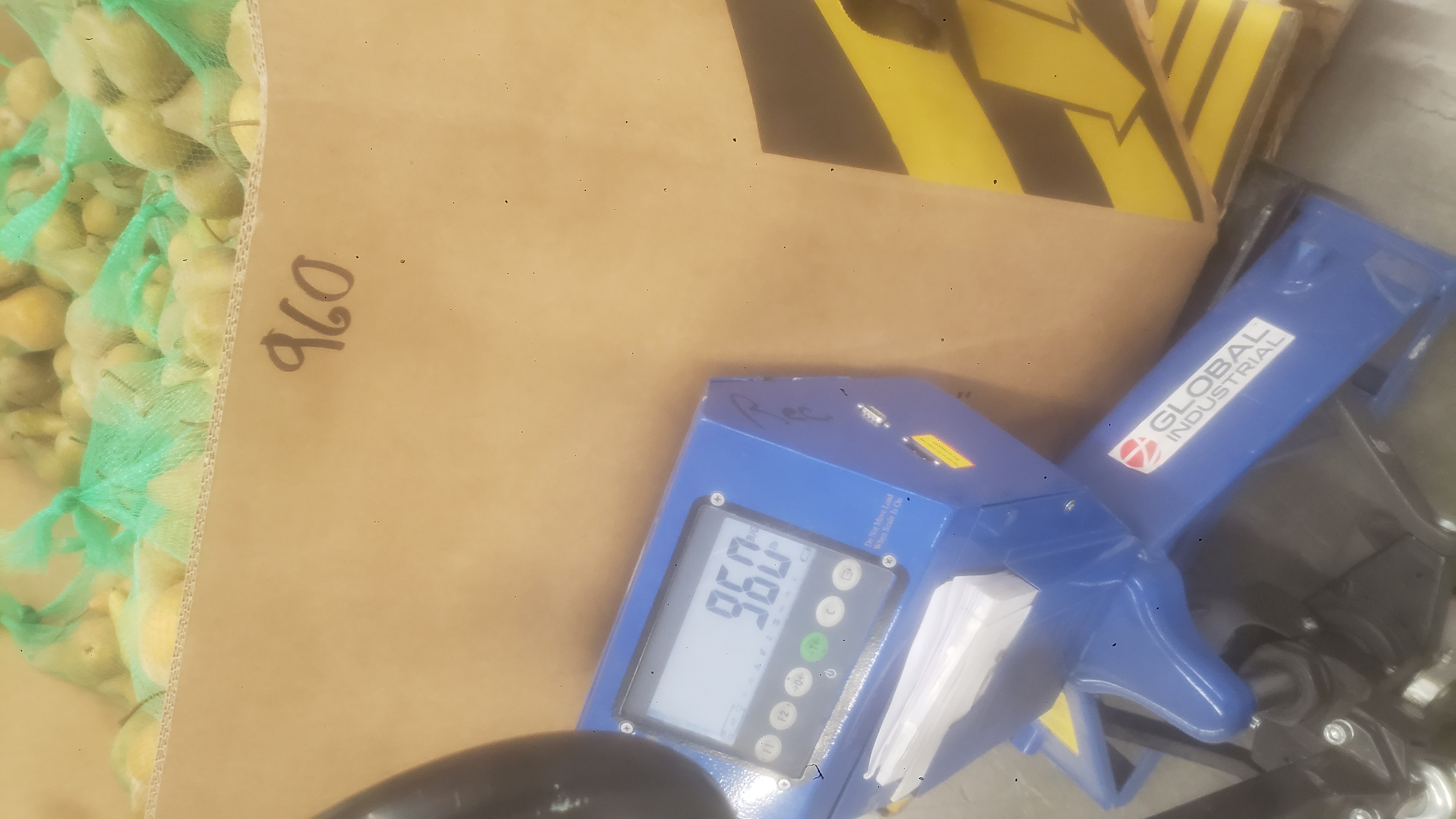 Bags of pears in a cardboard container on a weighted pallet jack that reads as 960.