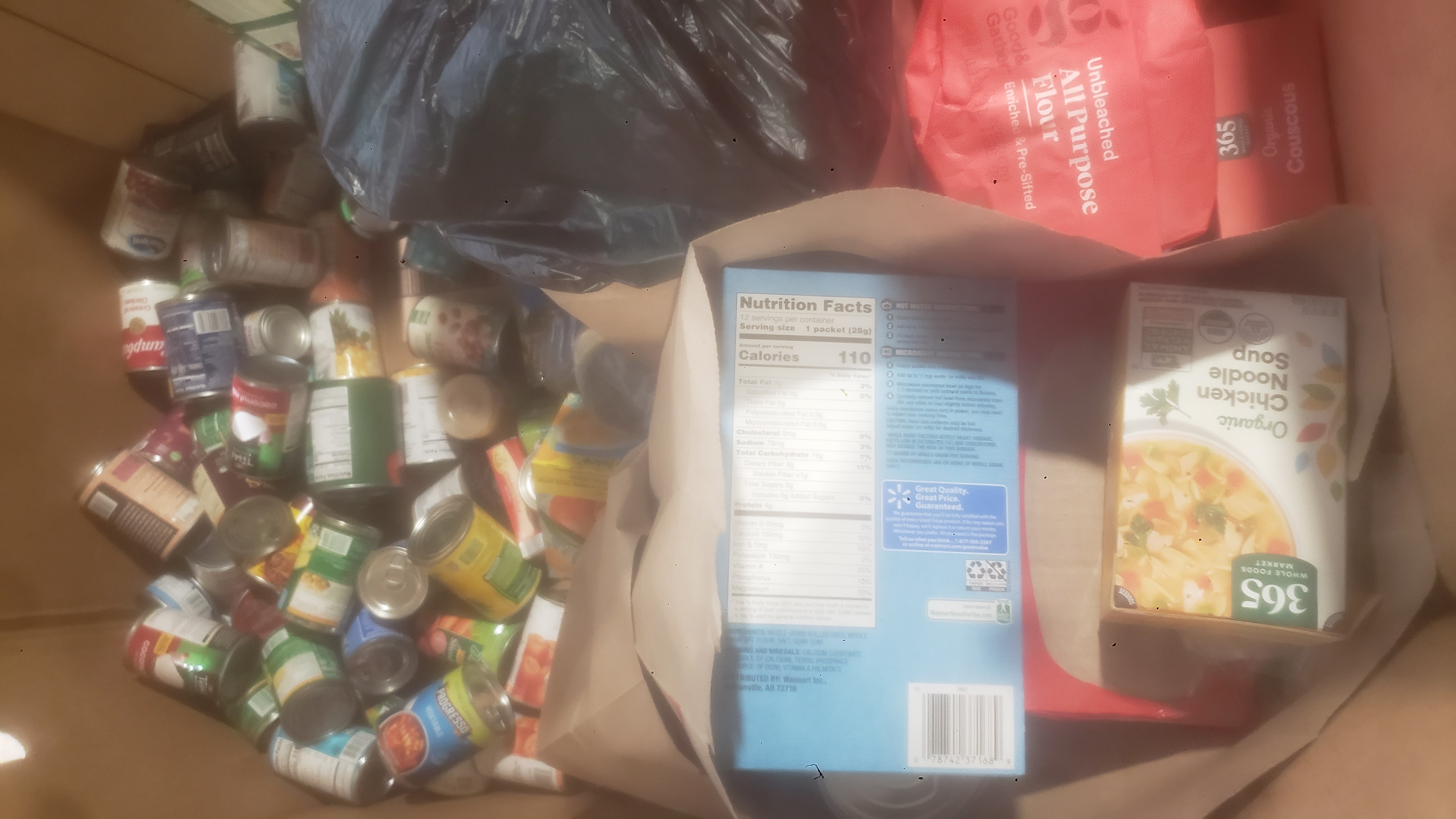 Paper bags filled with food and ingredients in a cardboard container.