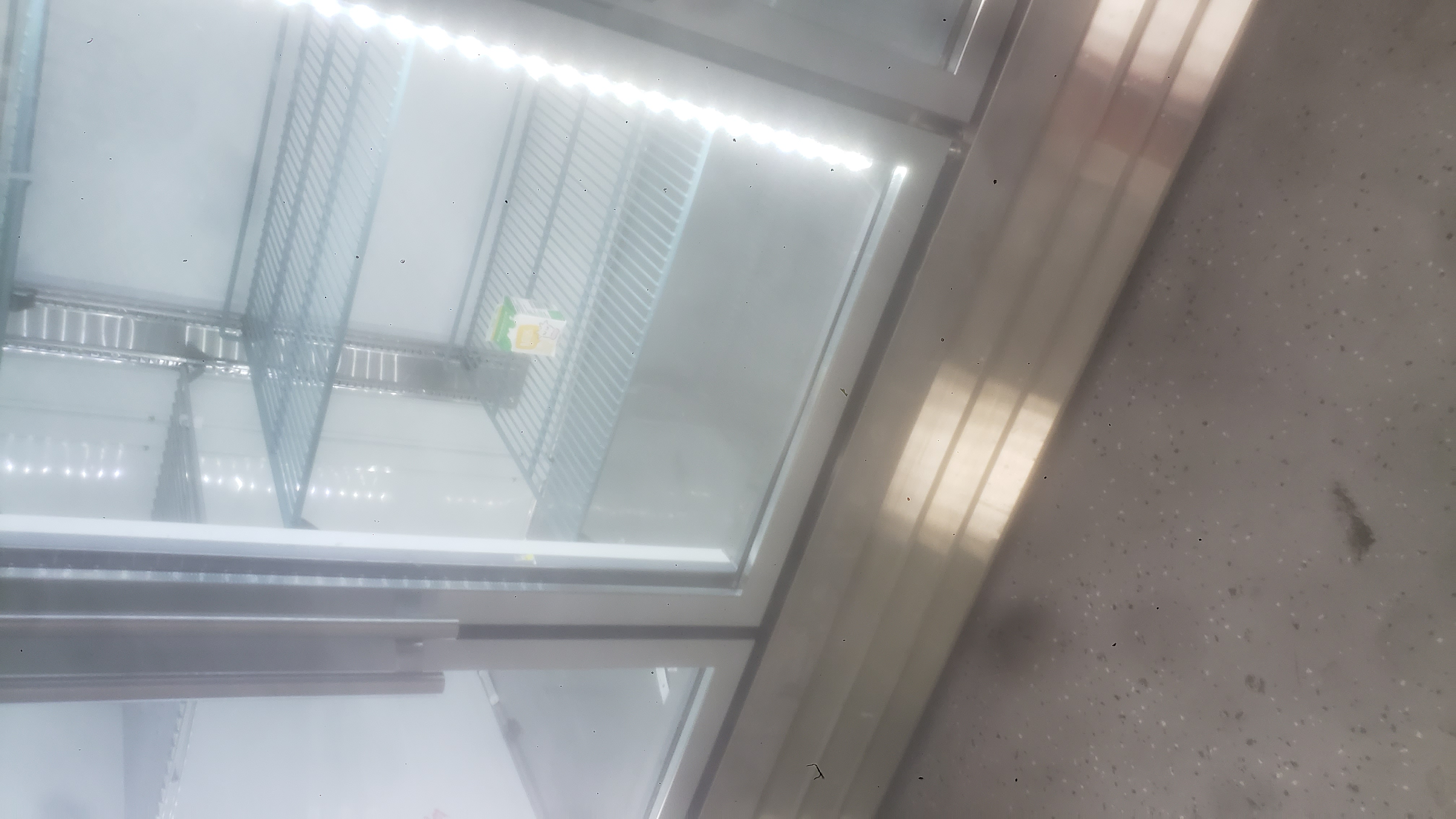 One single half pint milk carton on a shelf in a fridge.