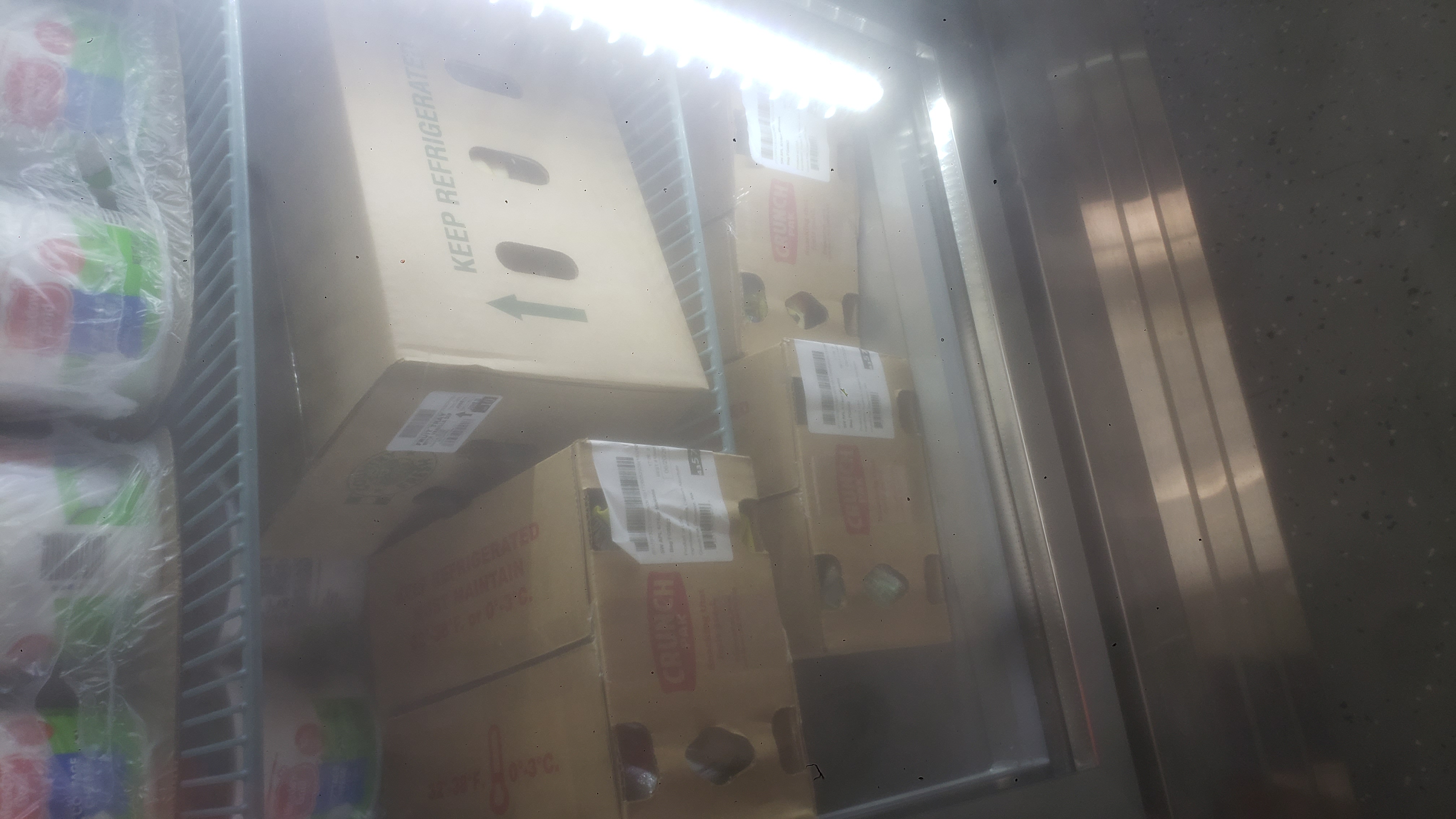 Tubs of cottage cheese, and boxes of snack packs on shelves of a fridge.