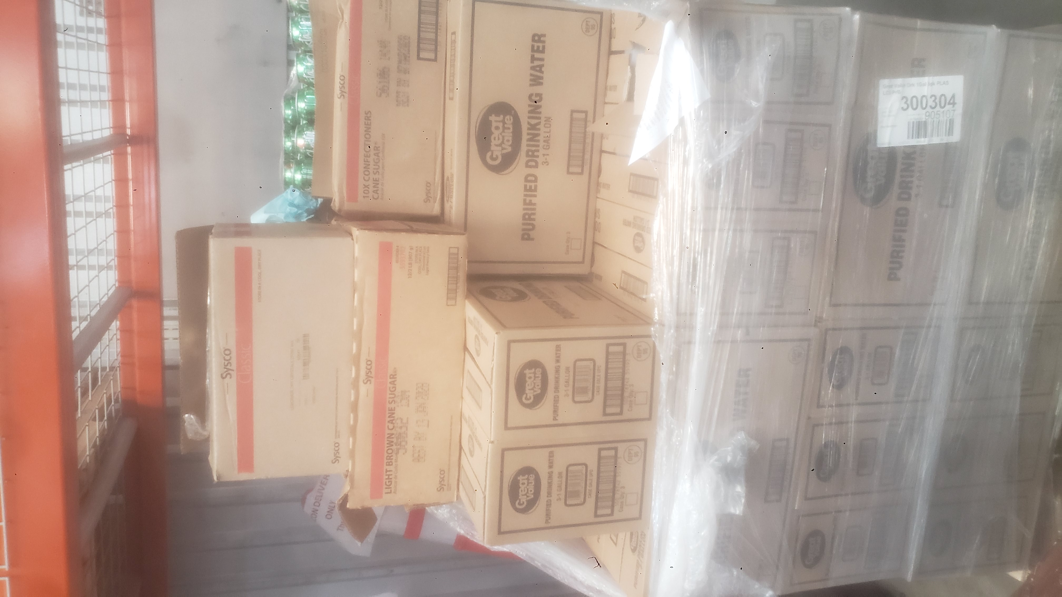 Boxes of distilled water, box of light brown sugar, box of powdered sugar, and case of shasta twist covered in plastic wrap on a pallet.