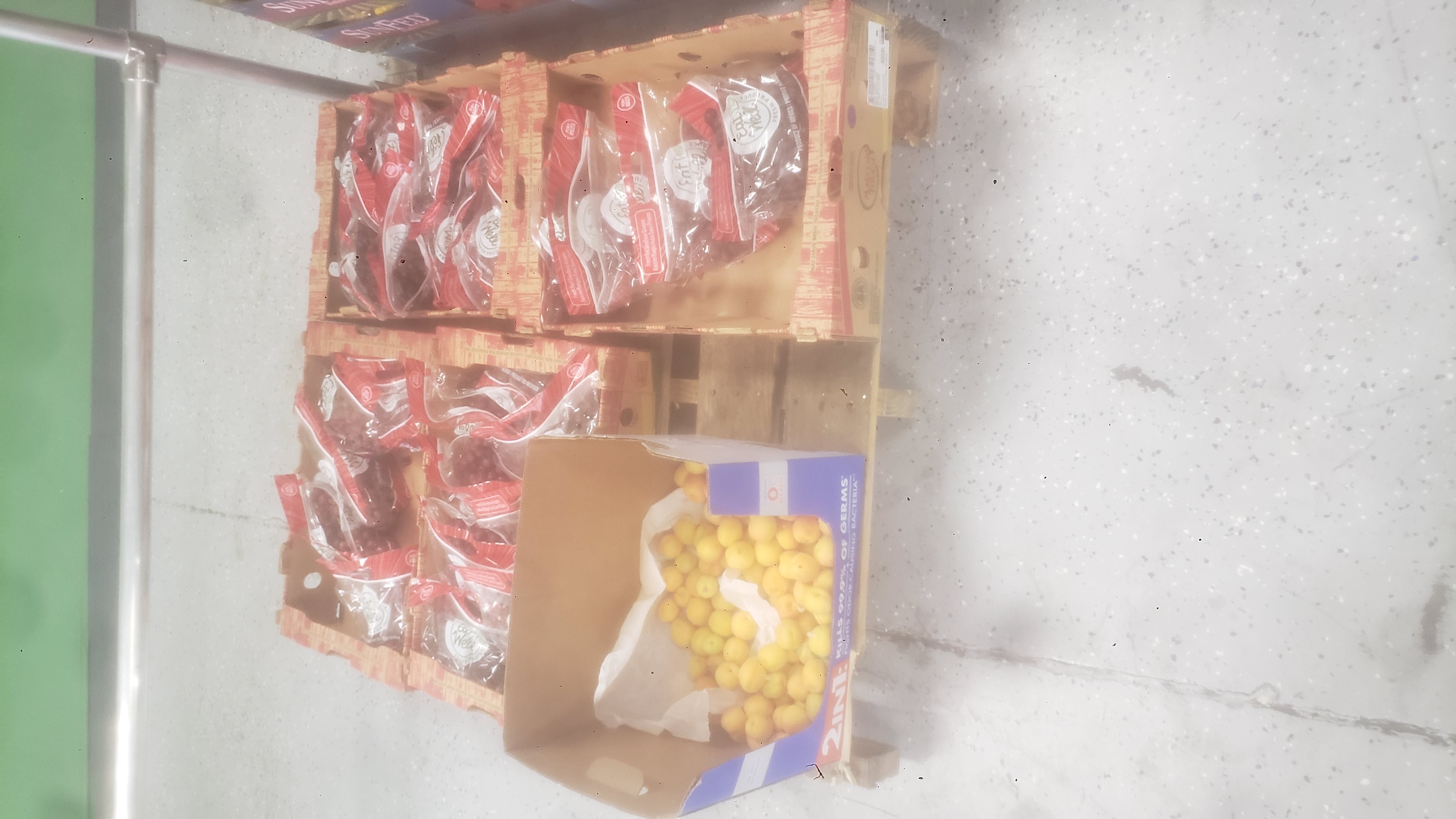 Trays filled with bags of red grapes and a tray of apricots on a pallet.