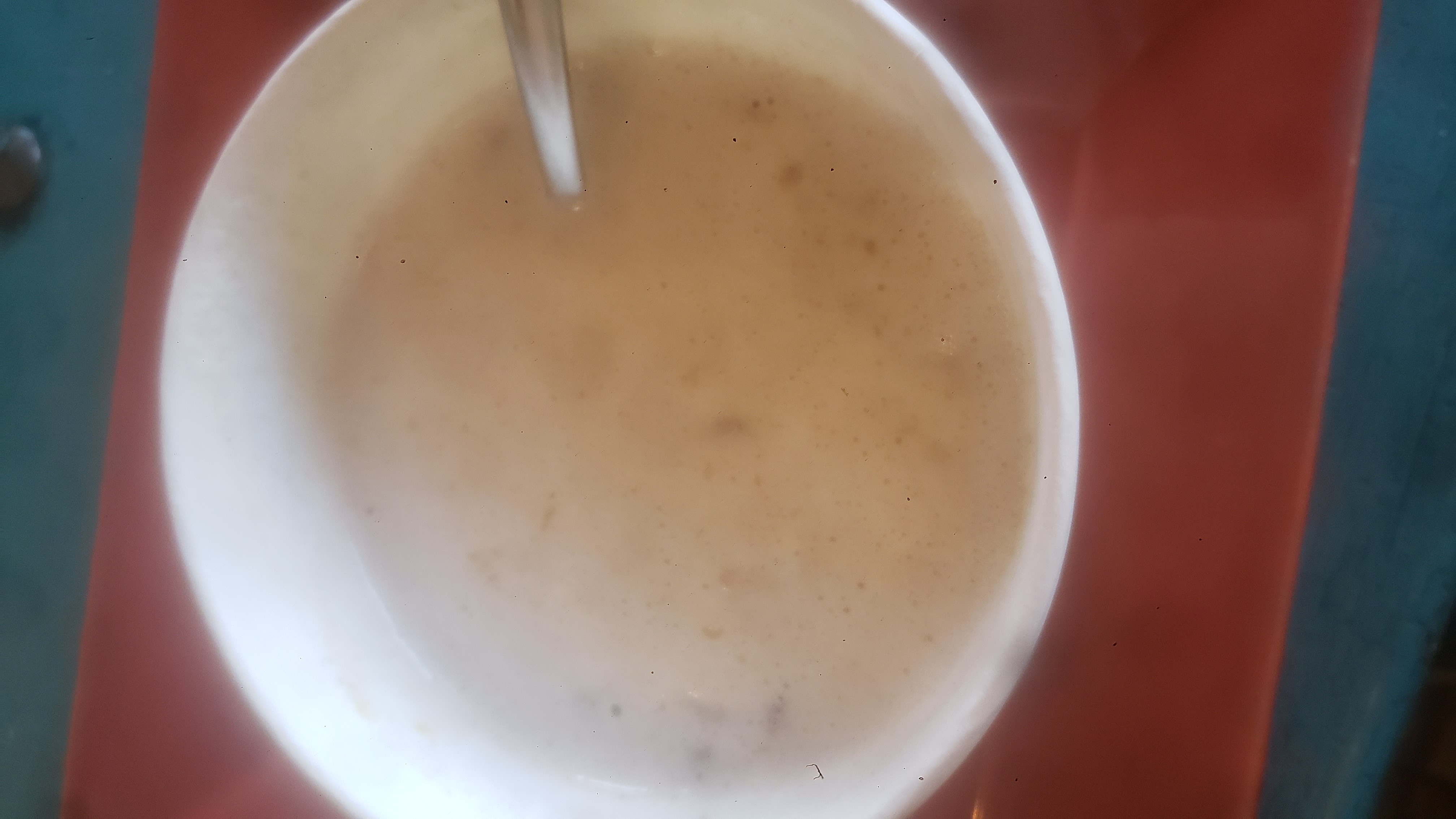 Paper cup of oatmeal with spoon.