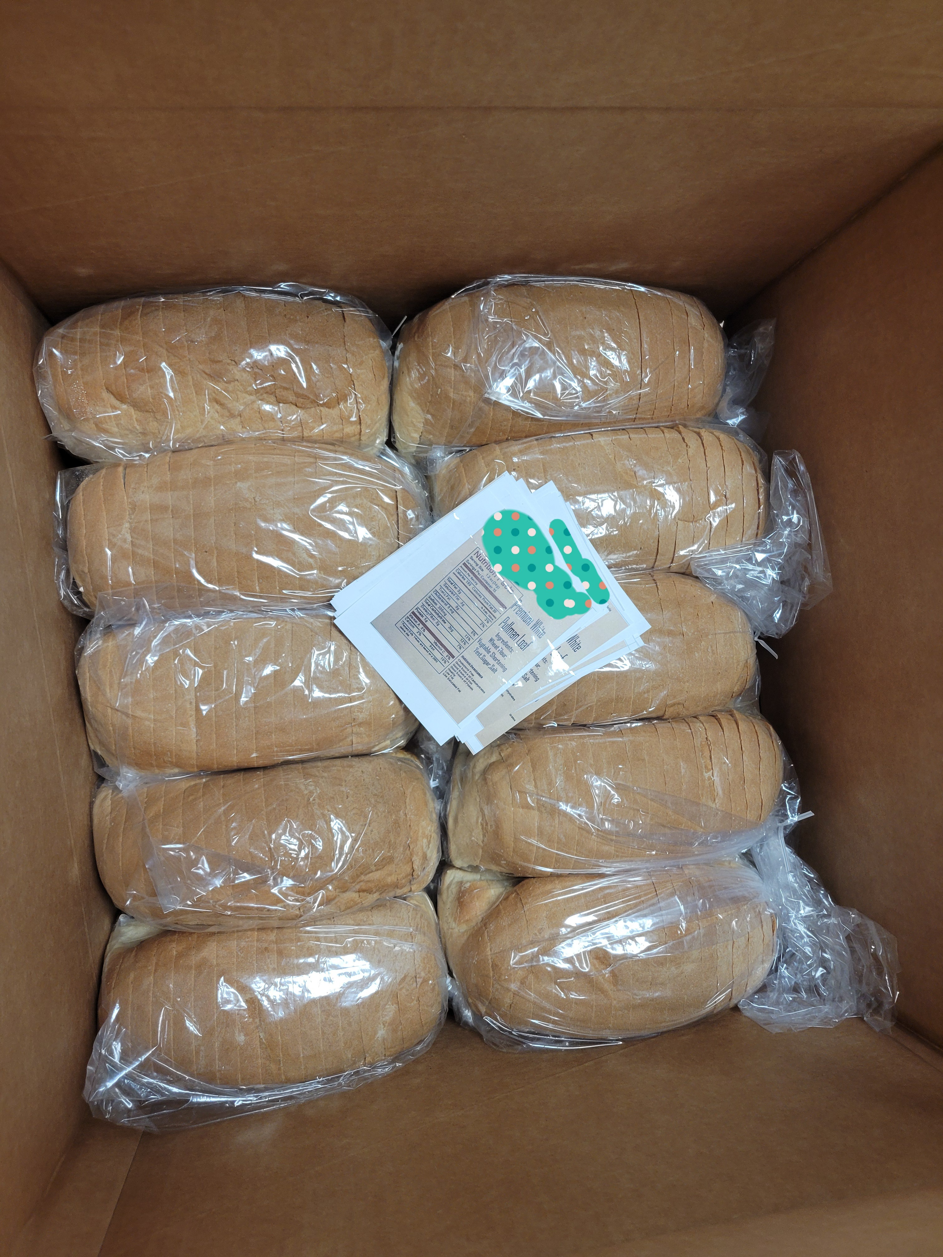 Cardboard box filled with loaves of bread and nutrition labels of the local bakery bread.