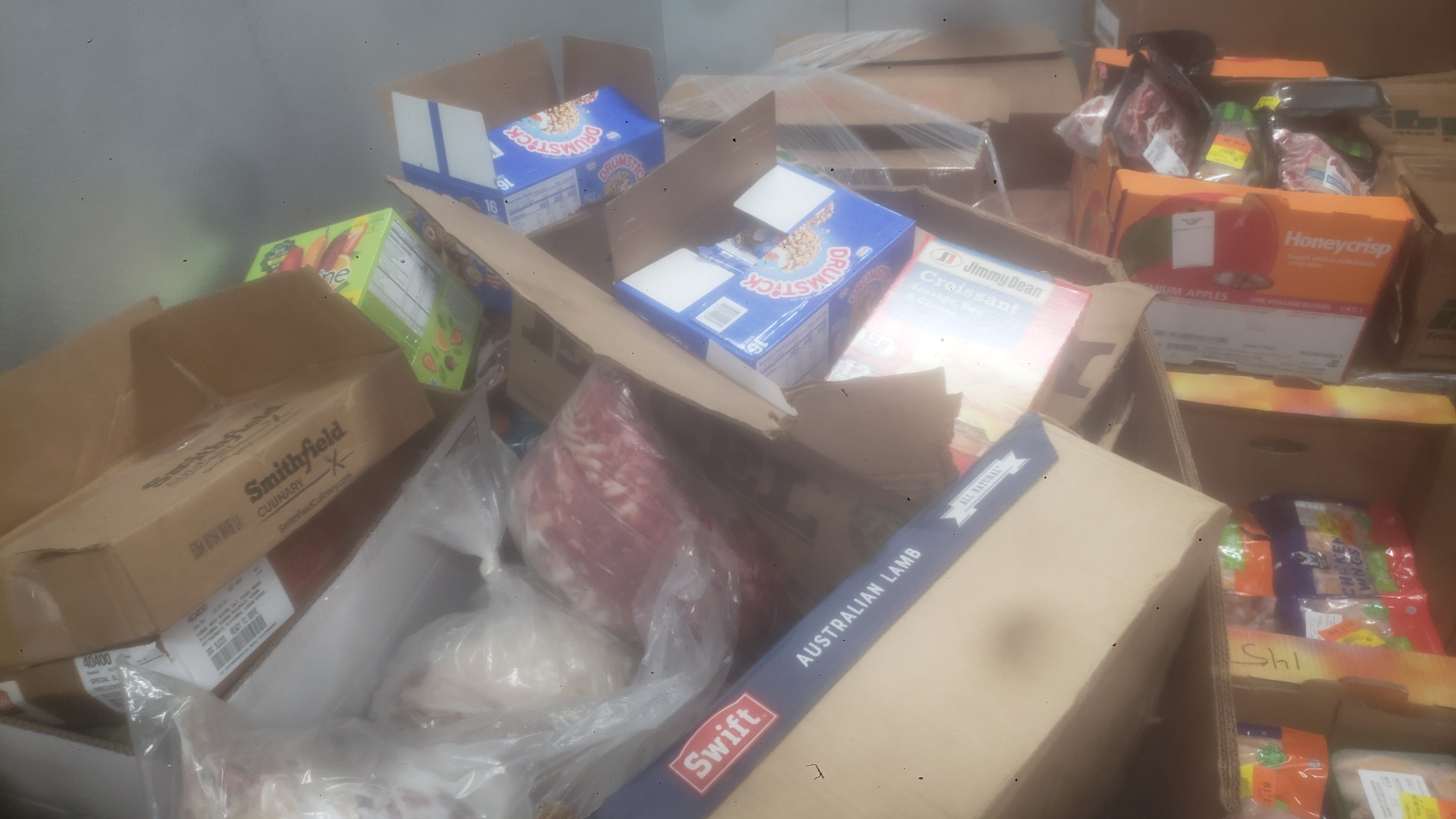 Assorted frozen items in cardboard boxes such as lamb, fruit popsicle, and beef.
