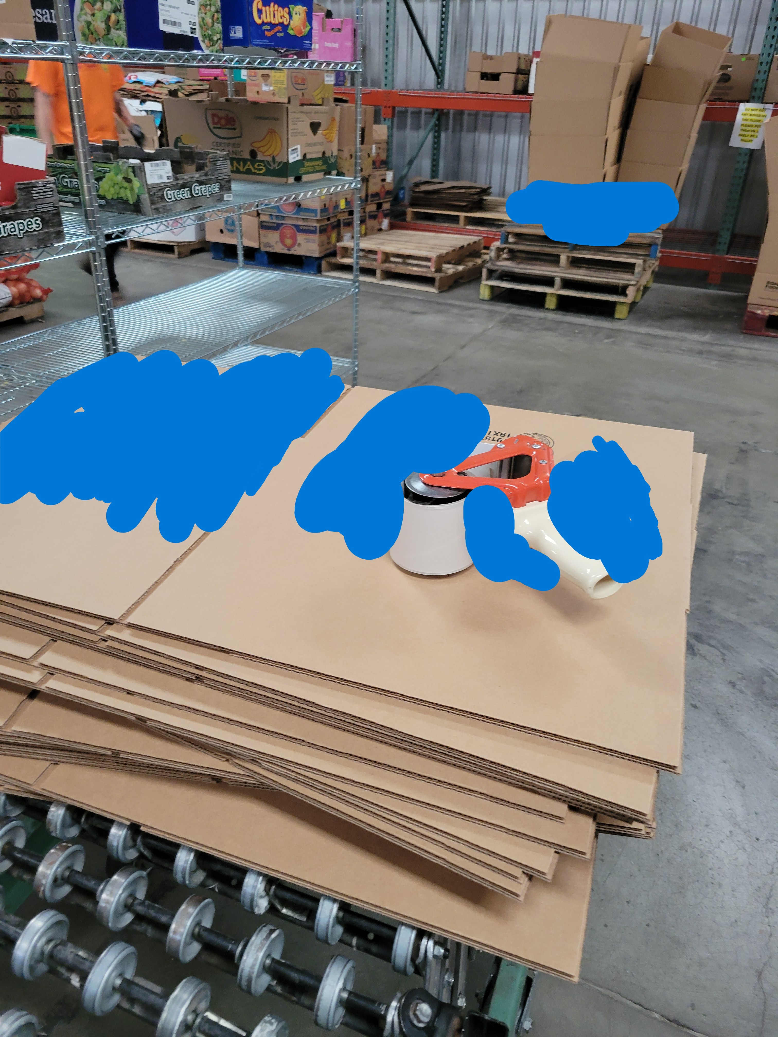 Untaped cardboard boxes with tape gun on top of it on a conveyor belt.