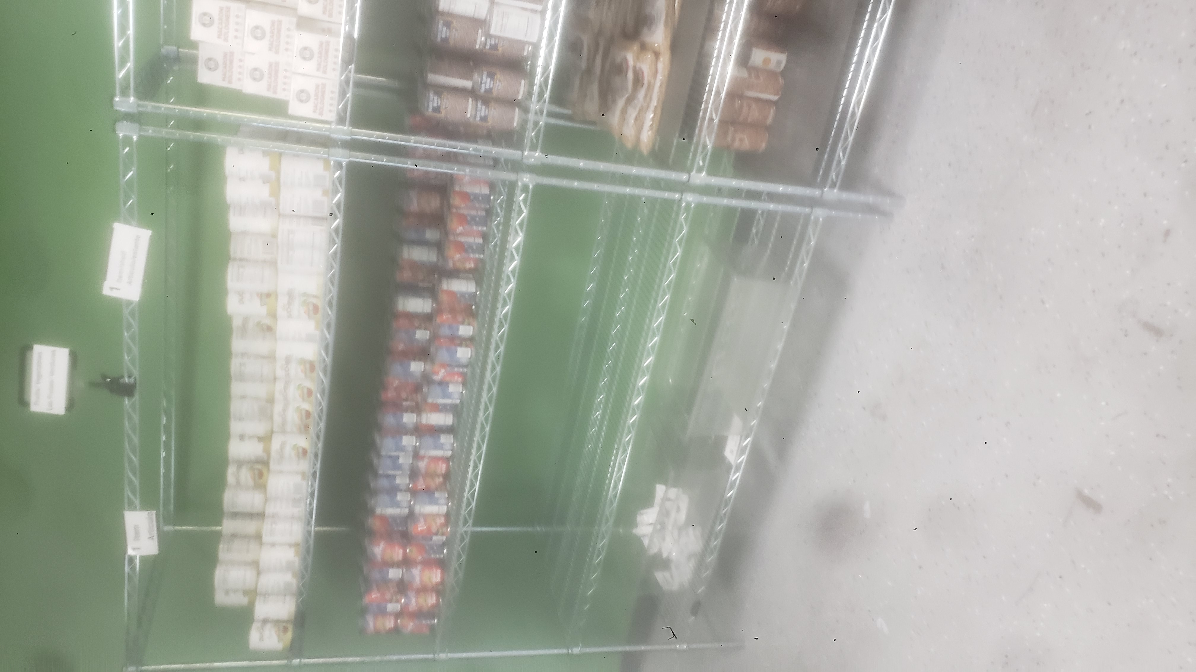 Canned applesauces, canned tomatoes sauces, and packets of dried cranberries on a four tier shelf.