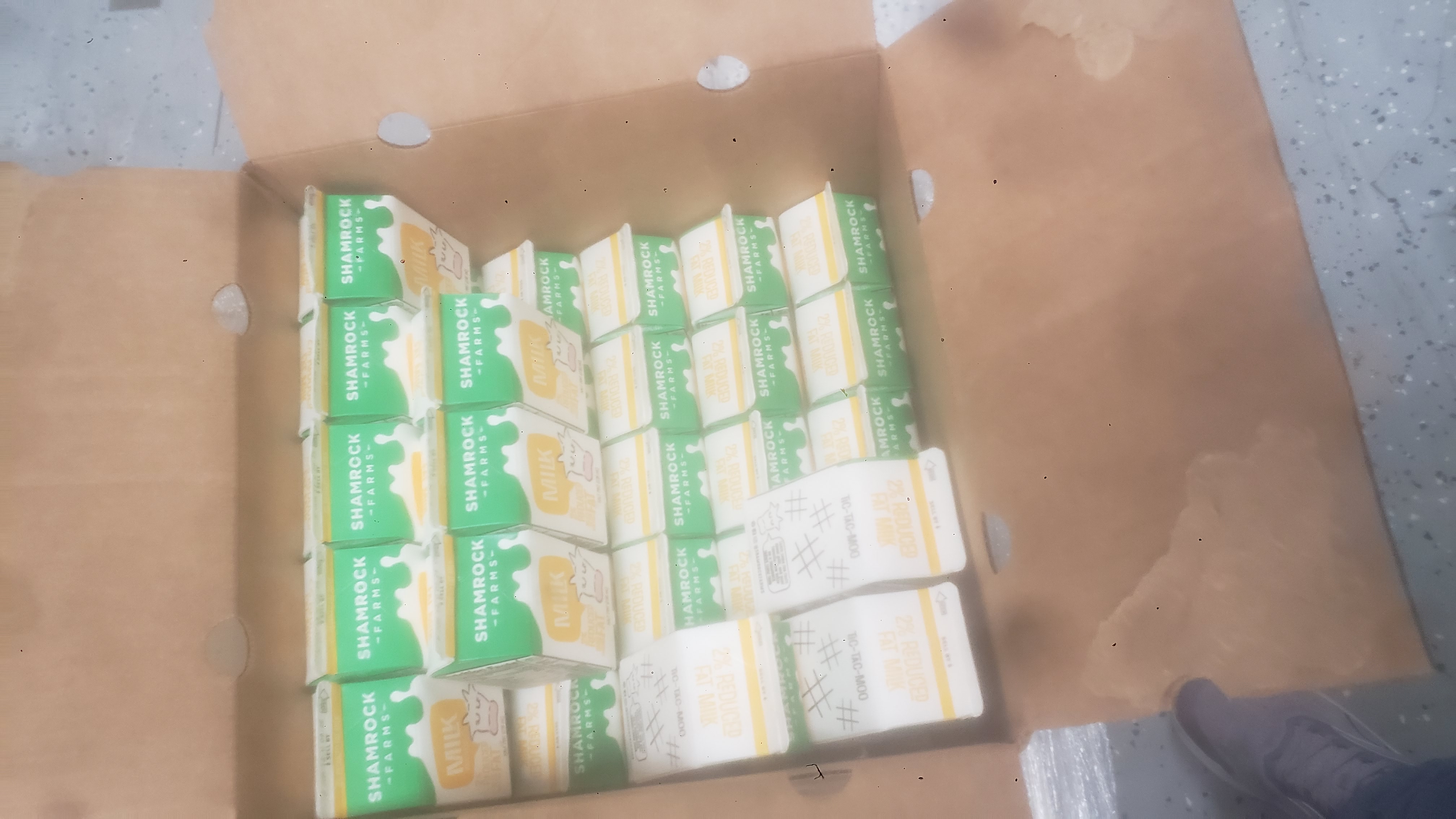 Cardboard box full of half pint 2% reduced fat milk cartons.