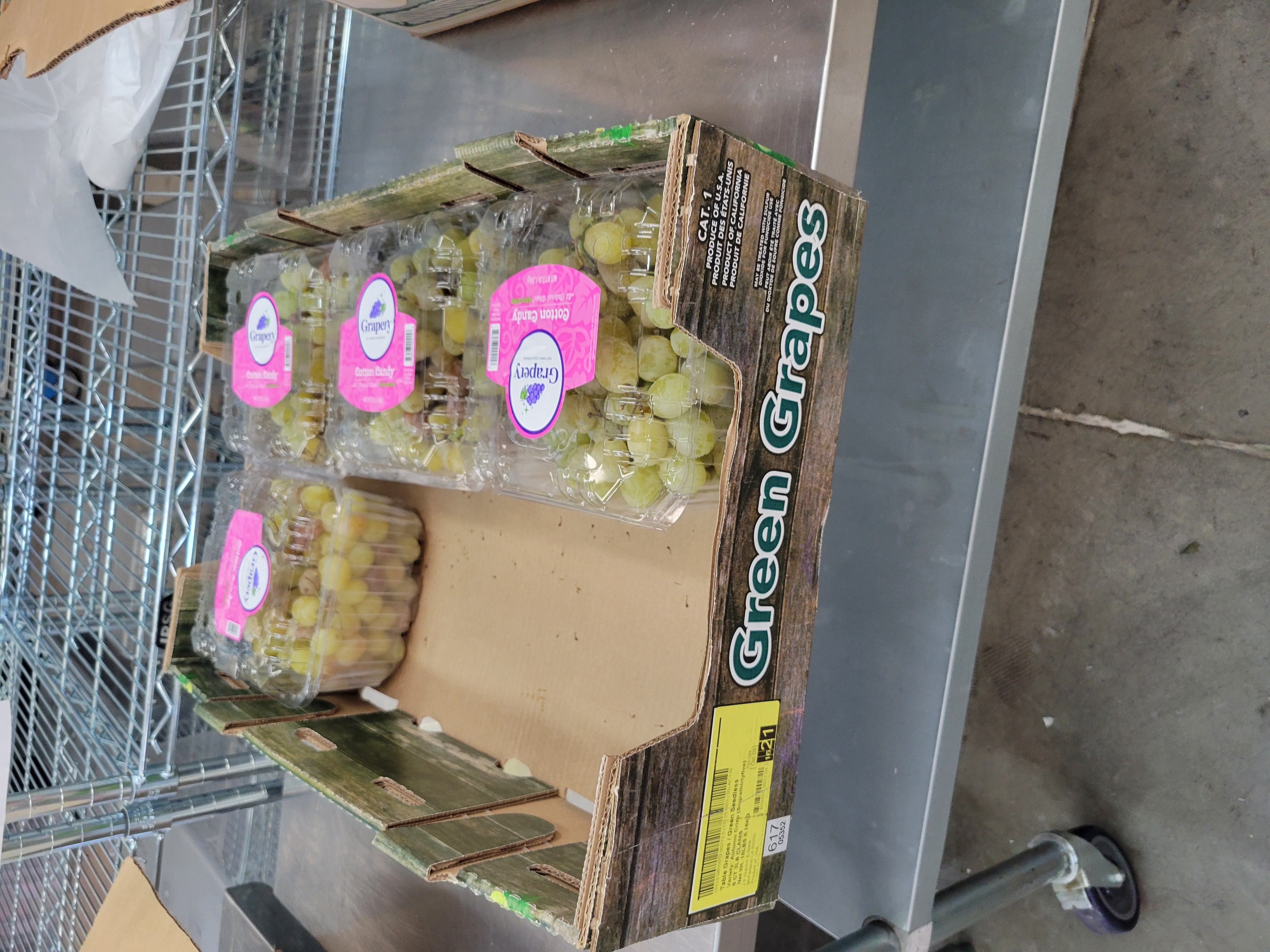 Clam shell containers of green grapes in a produce tray.