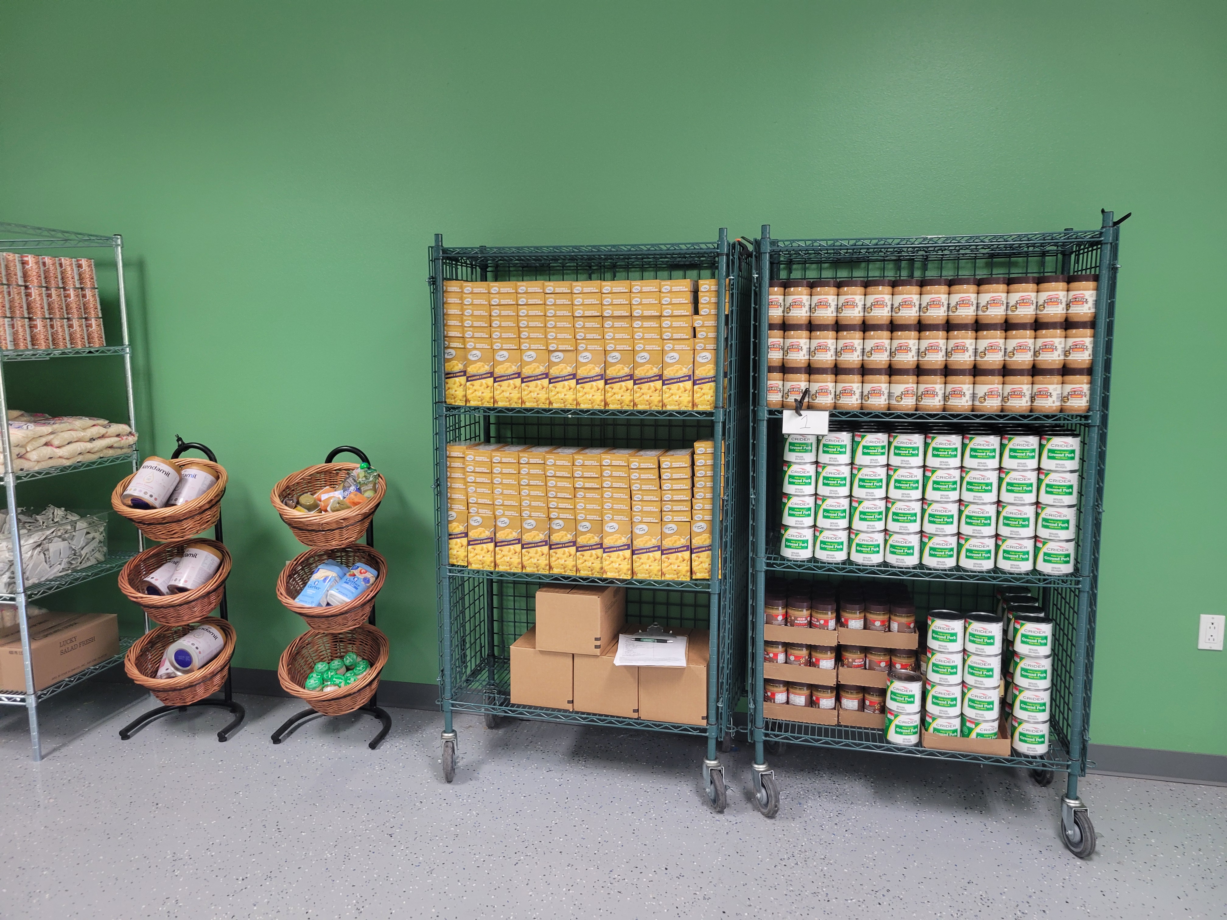 Three shelves of food with two 3 tier mobile display baskets between filled with food.